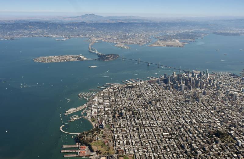 Aerial view of San Francisco, the bay waters, the Bay Bridge and islands in the bay.