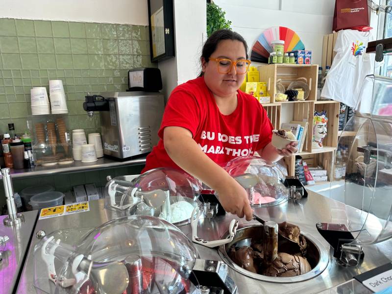 An employee scoops gelato in an ice cream shop.