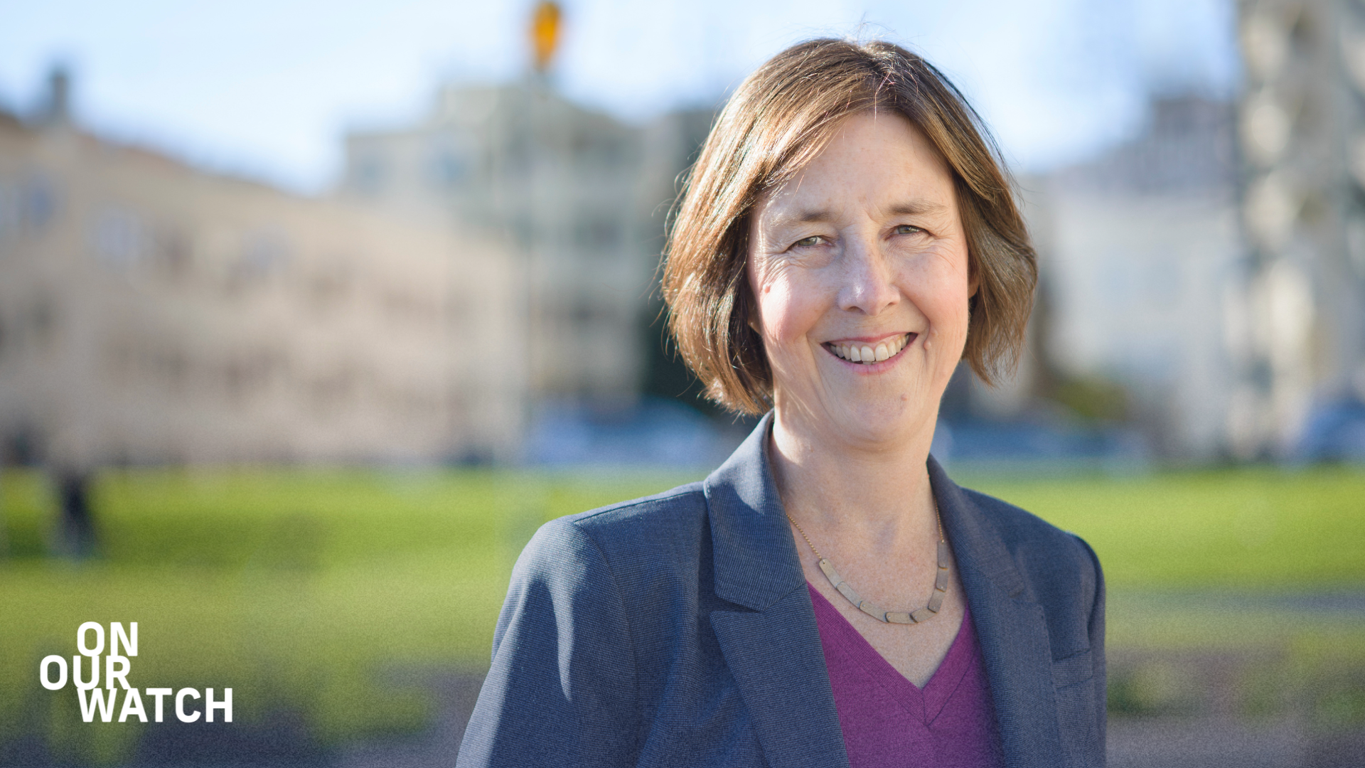 Portrait of California State Senator Nancy Skinner, a white, middle-aged woman with chin-length brown hair. She is smiling and wearing a gray blazer over a purple top with a necklace. She is standing outside in front of an out-of-focus building. The background surrounding the portrait is blurred with gradient colors from blue to green. The text 'ON OUR WATCH' is written in the lower-left corner.
