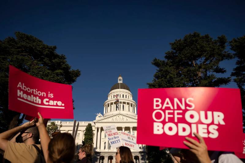 Pro-choice protesters rally in front of the California Capitol Building in Sacramento, holding signs that say 'Bans off our bodies.'