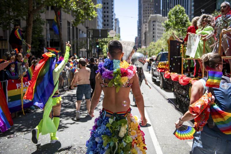 People in colorful costumes walk down the street in San Francisco.