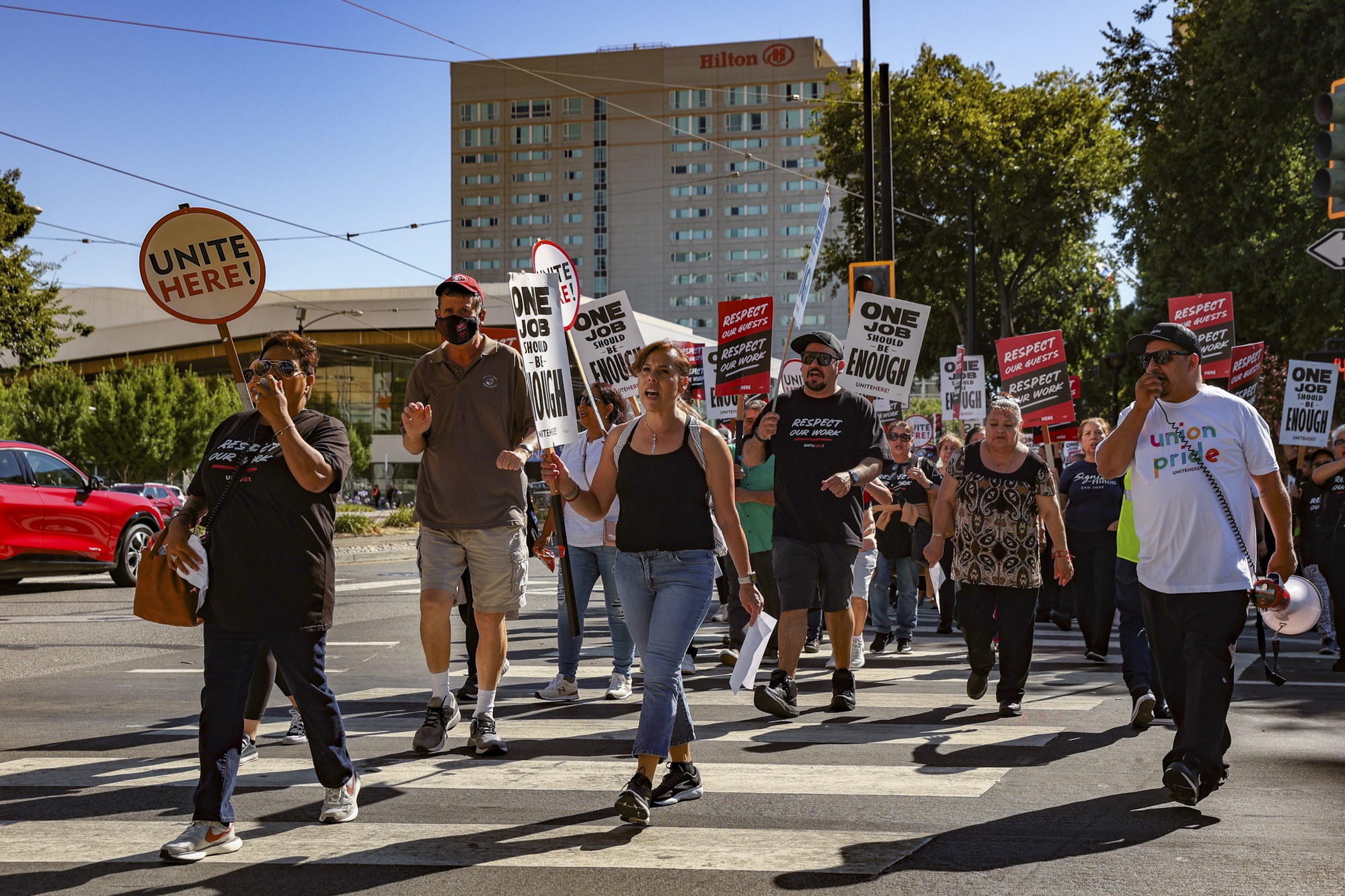Several people walk in the street holding signs.