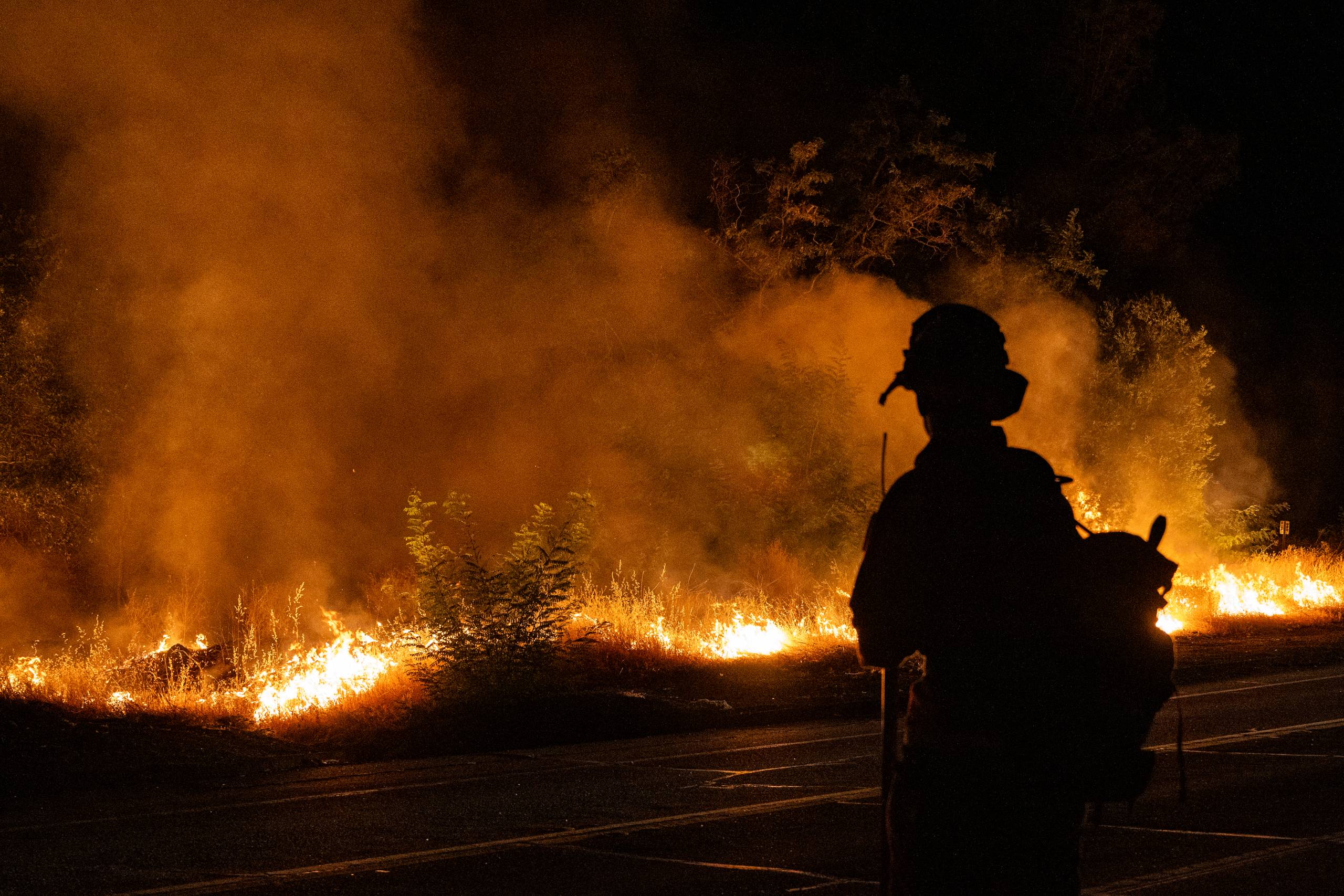 Profile of a person facing a fire with smoke in the background.