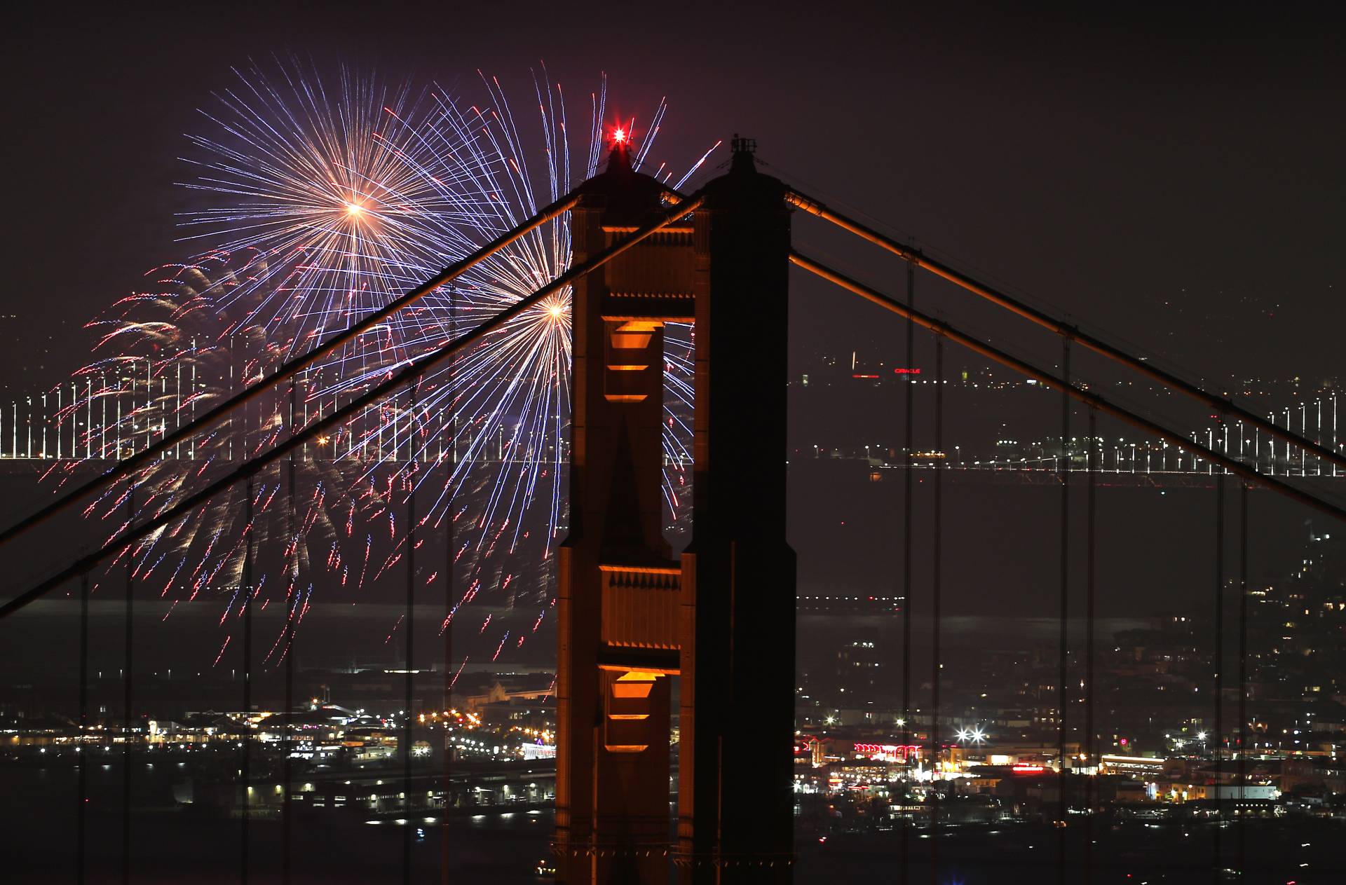 A display of fireworks at night by a bridge.