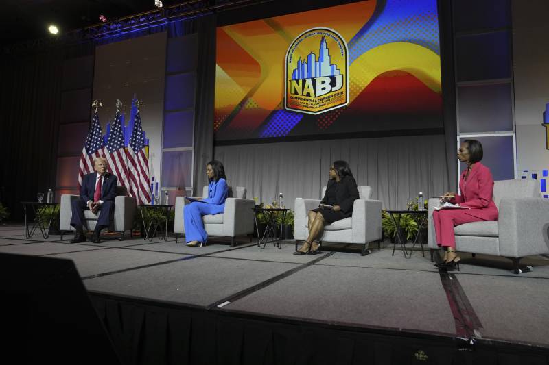 People sitting on a stage in white couches.