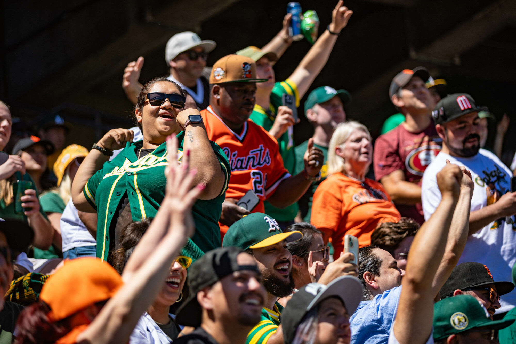 Several fans wearing green and orange cheer in the stands.