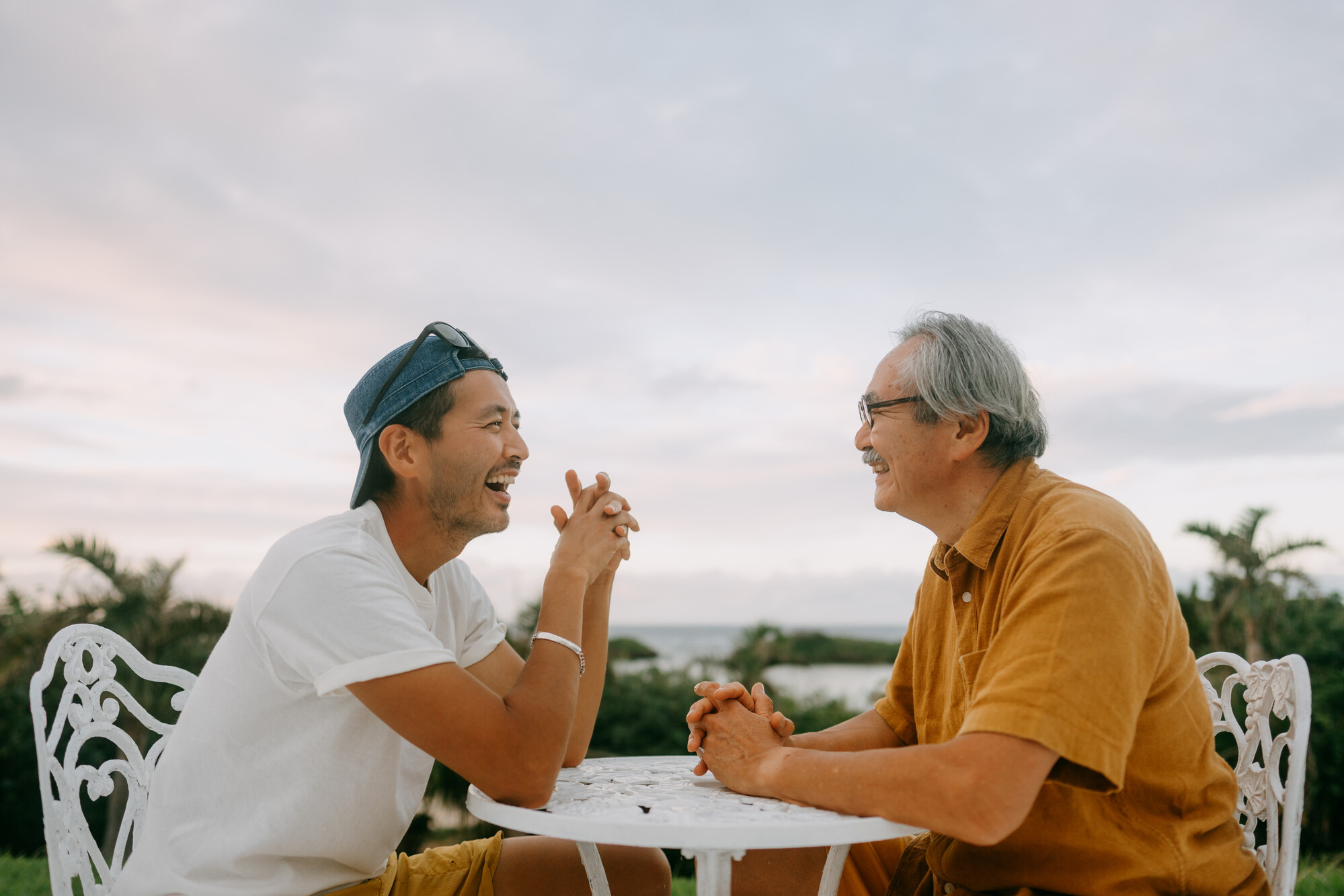Father and son sit at a table talking.