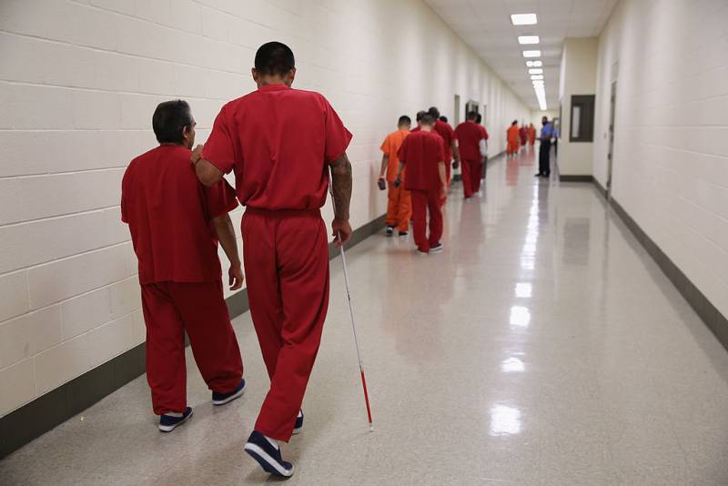 Immigrant detainees walk down a hallway.