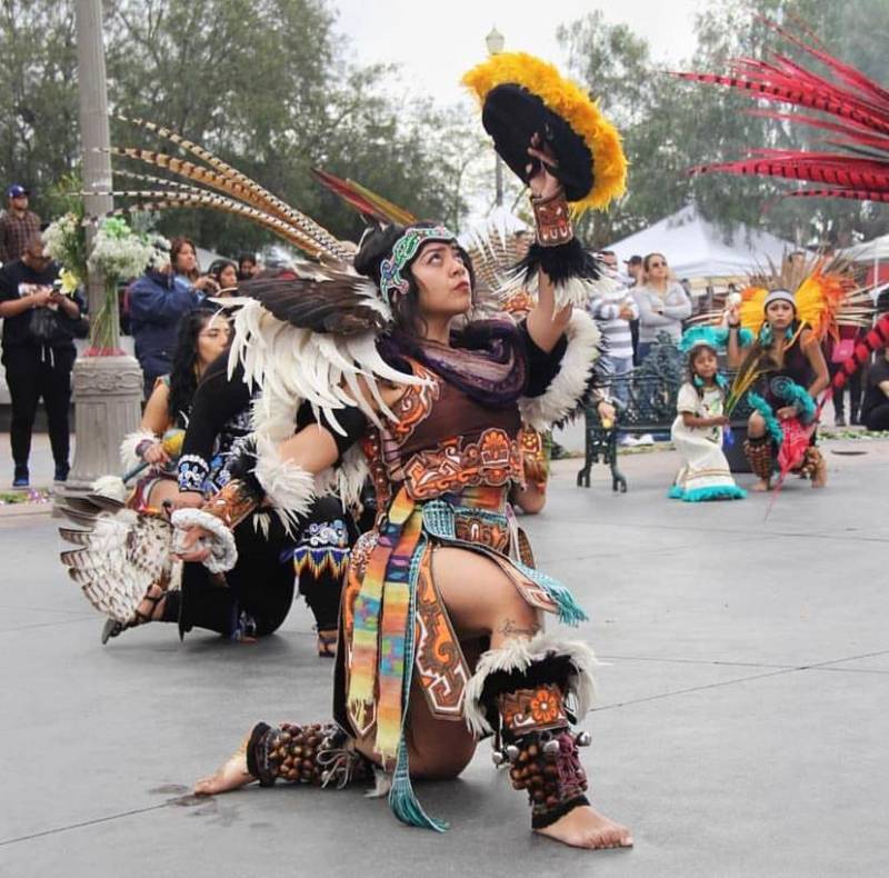 A woman in an ornate dance dress performs on the street.