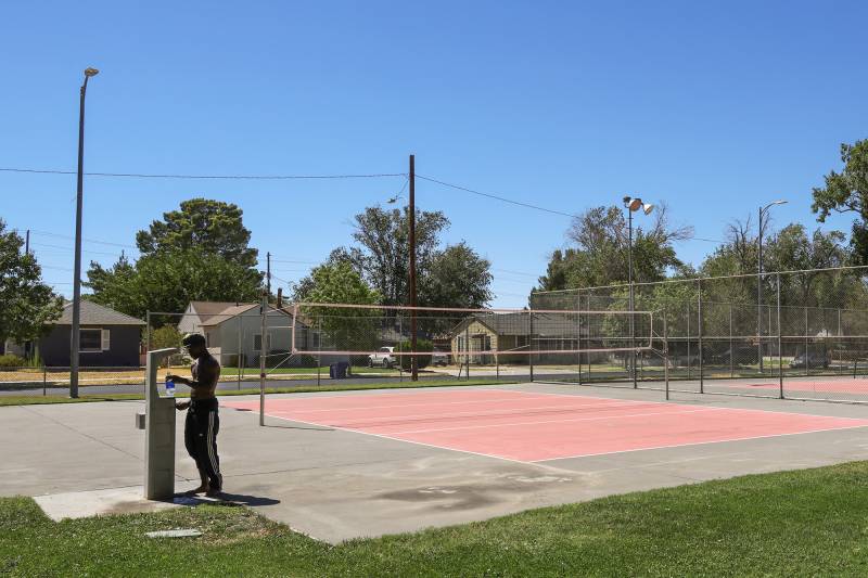 A person fills their water bottle at an empty tennis court.