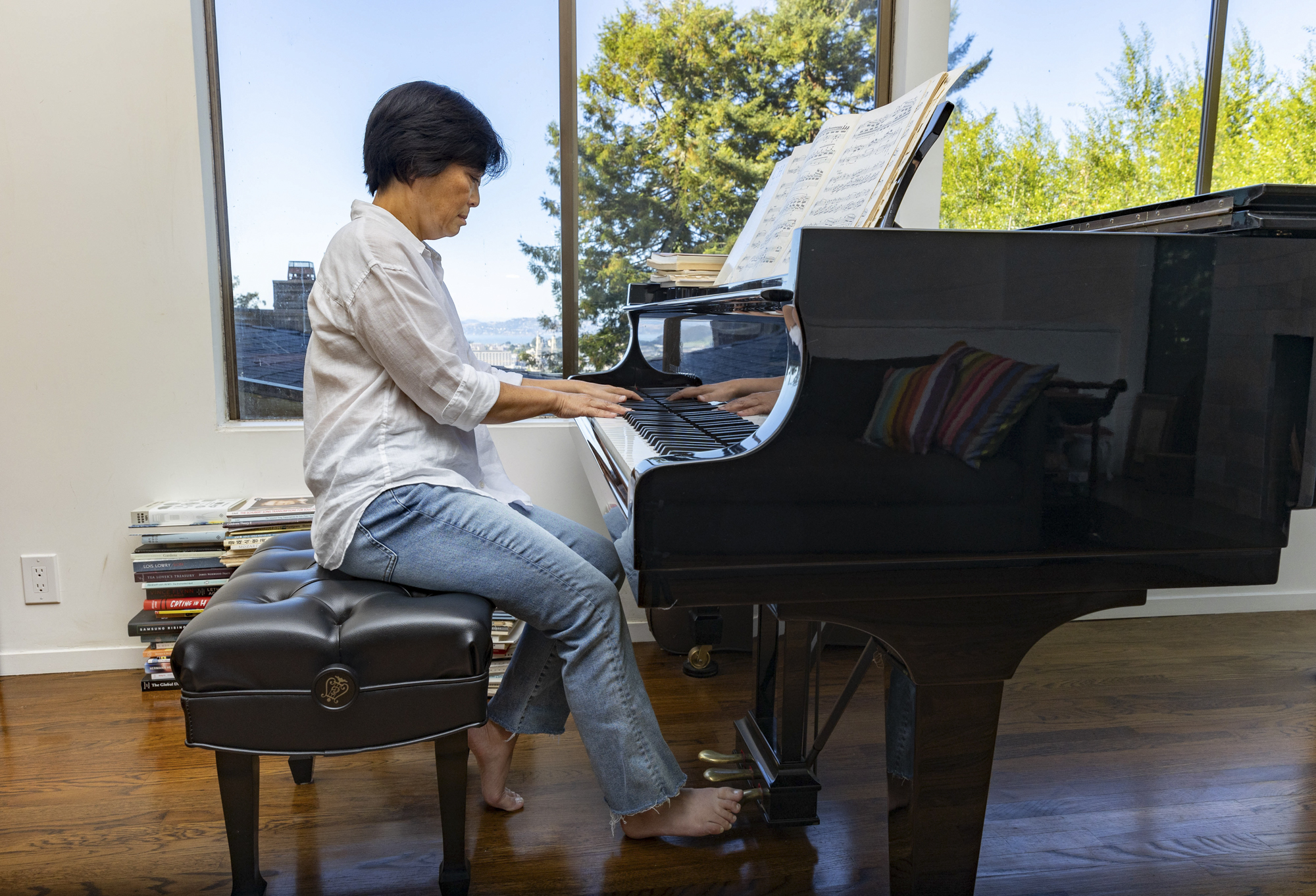 An Asian woman sits playing a grand piano.