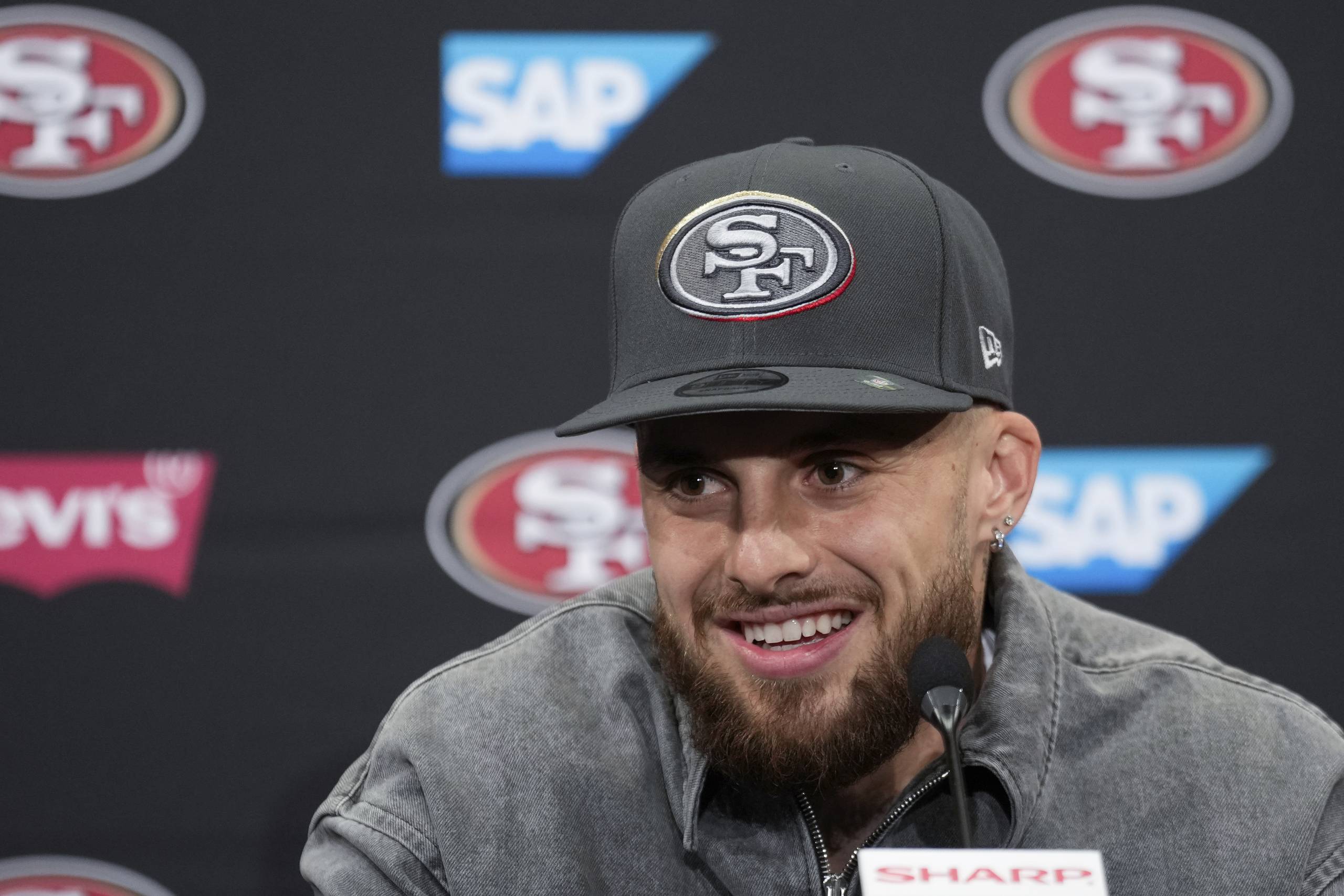 A man in a black hat speaks at a press conference.