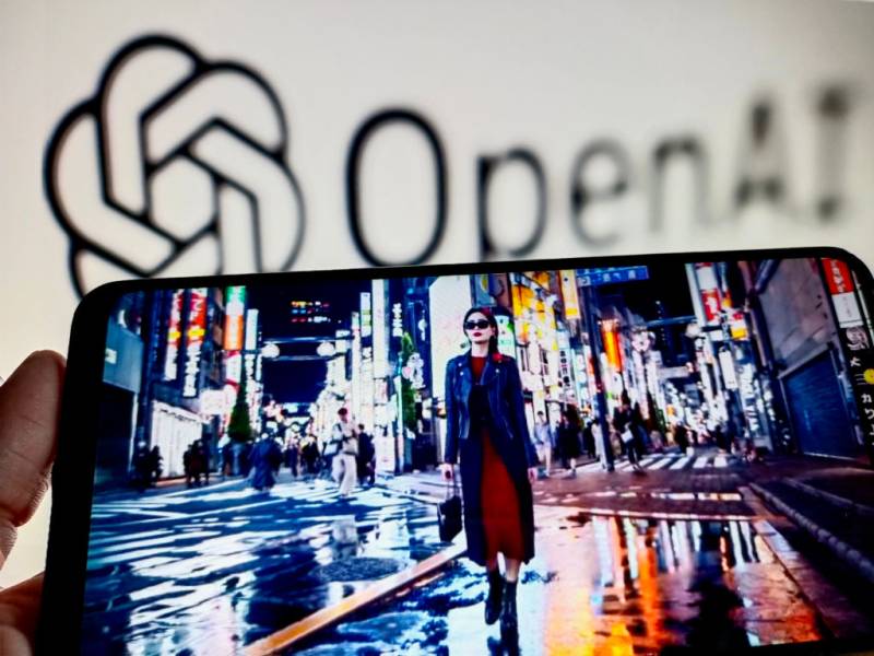 A hand holds a tablet with an image of a woman walking through a city street at night with the Open AI logo in the background.