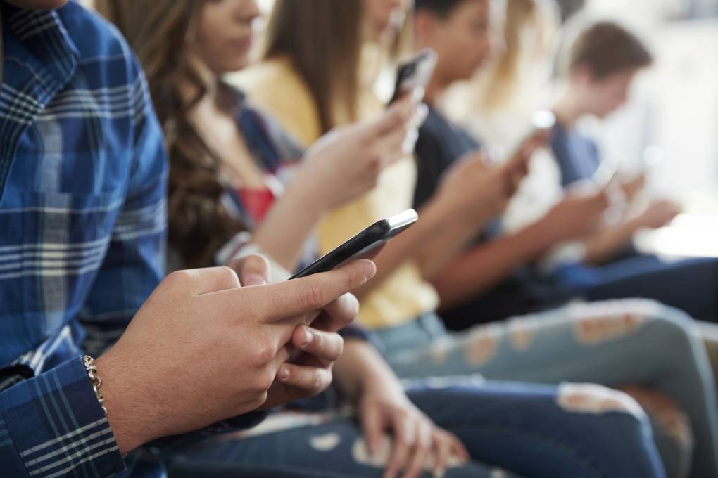 A close up of a line of students using mobile phones.