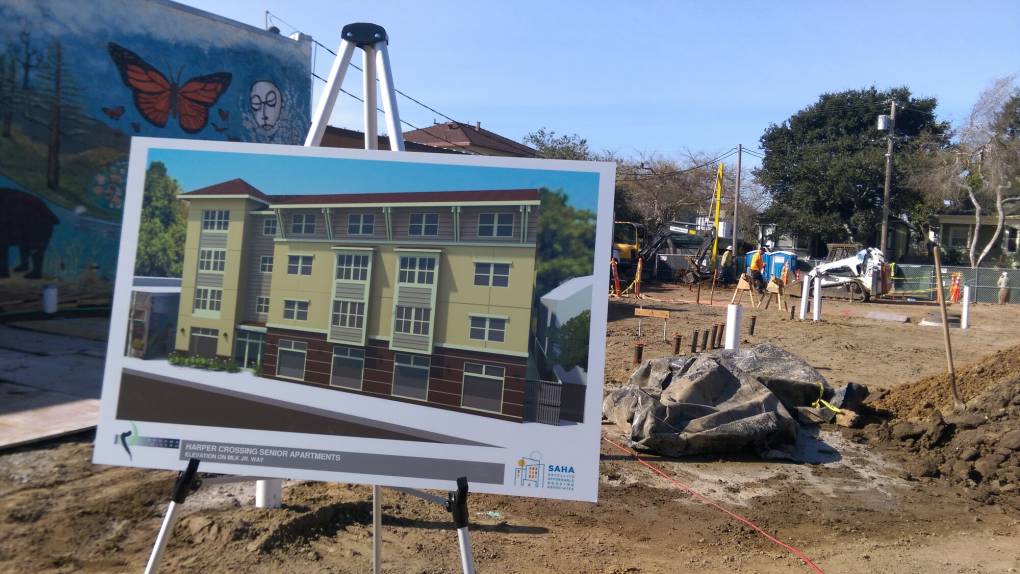 An easel displaying an image of a planned senior housing development sits on the open construction site where it will be built.