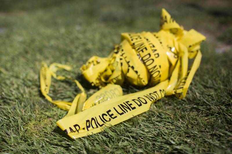 A bundle of yellow police scene tape on grass.