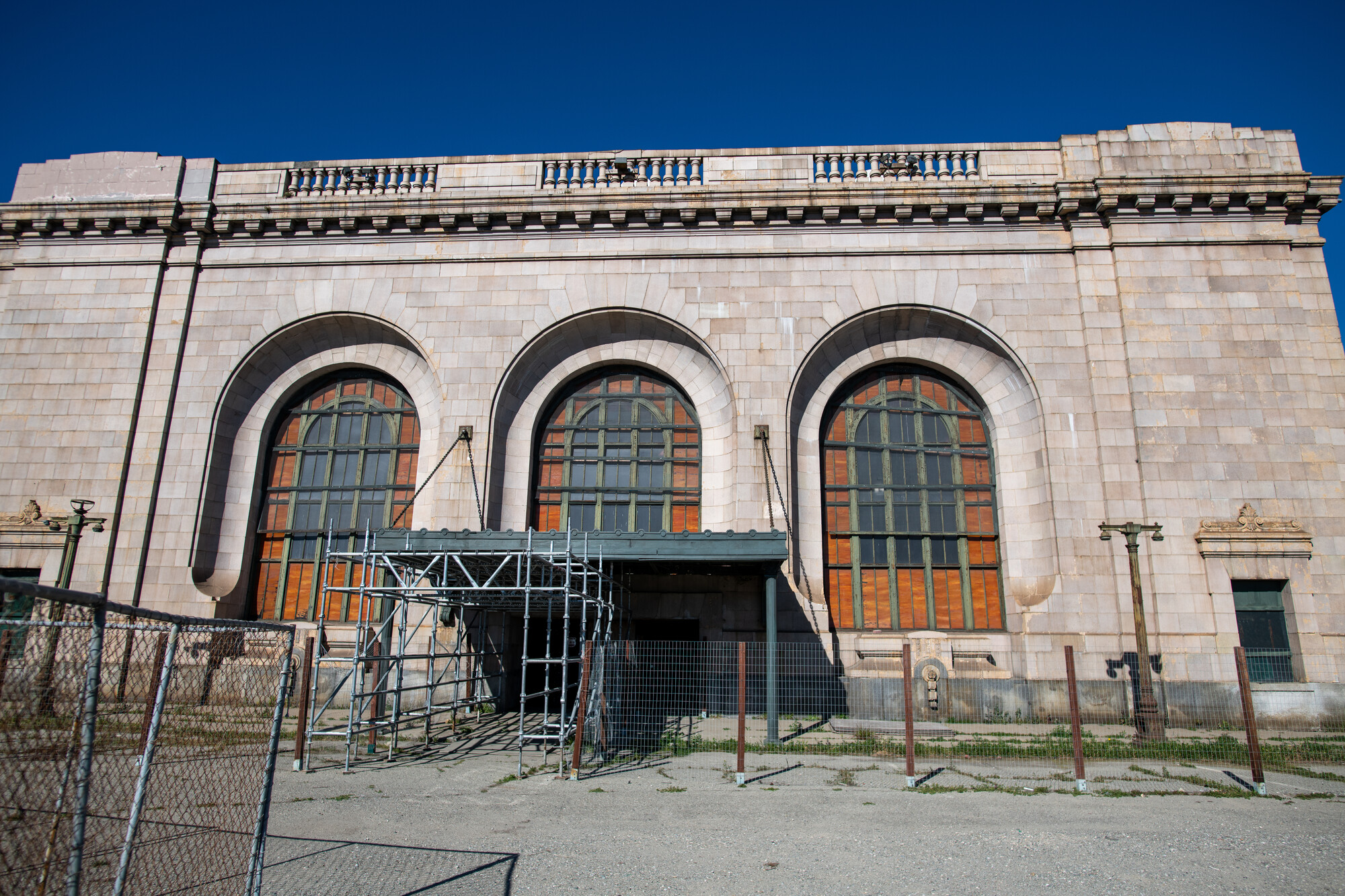 The front exterior of an abandoned building with fencing around it.