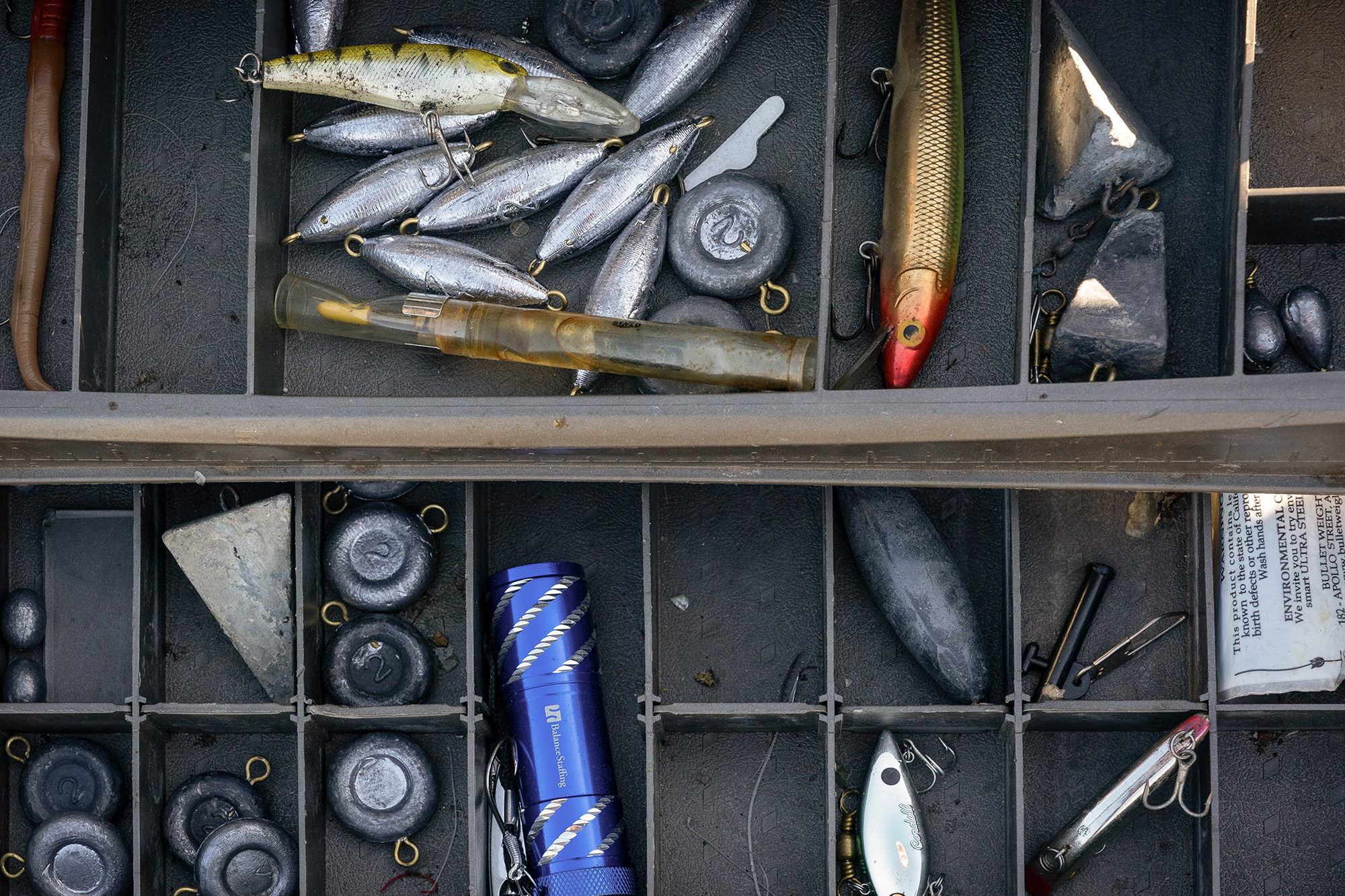 A tackle box with fishing gear in each space.