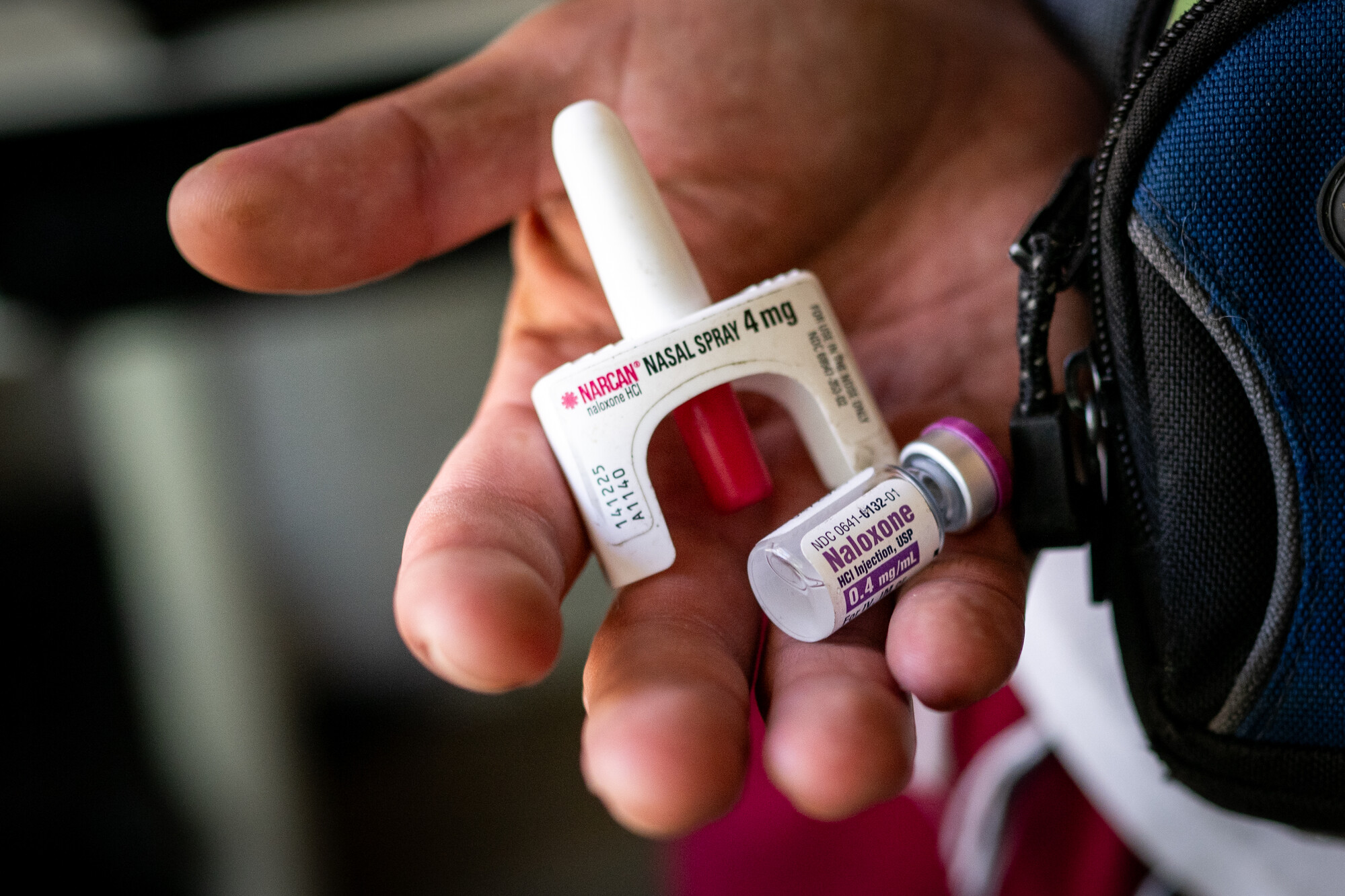 A hand holds a nasal spray and medication.