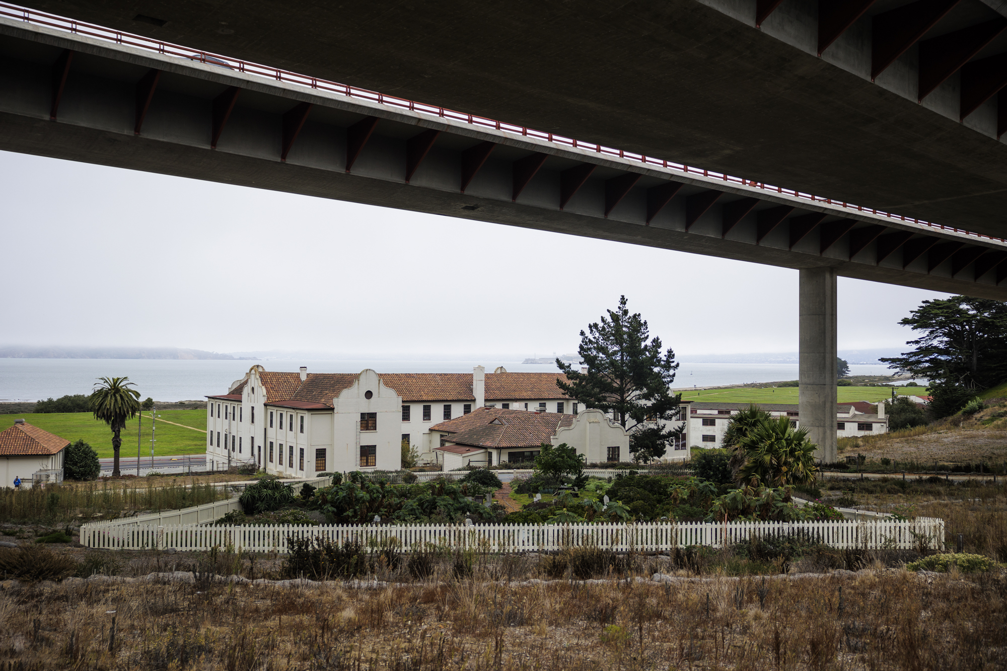 A building and cemetery in the distance underneath an overpass.