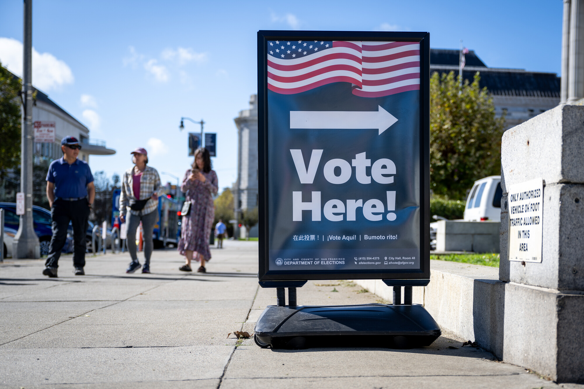 A sign says 'Vote Here!' with an arrow pointing to a polling place.