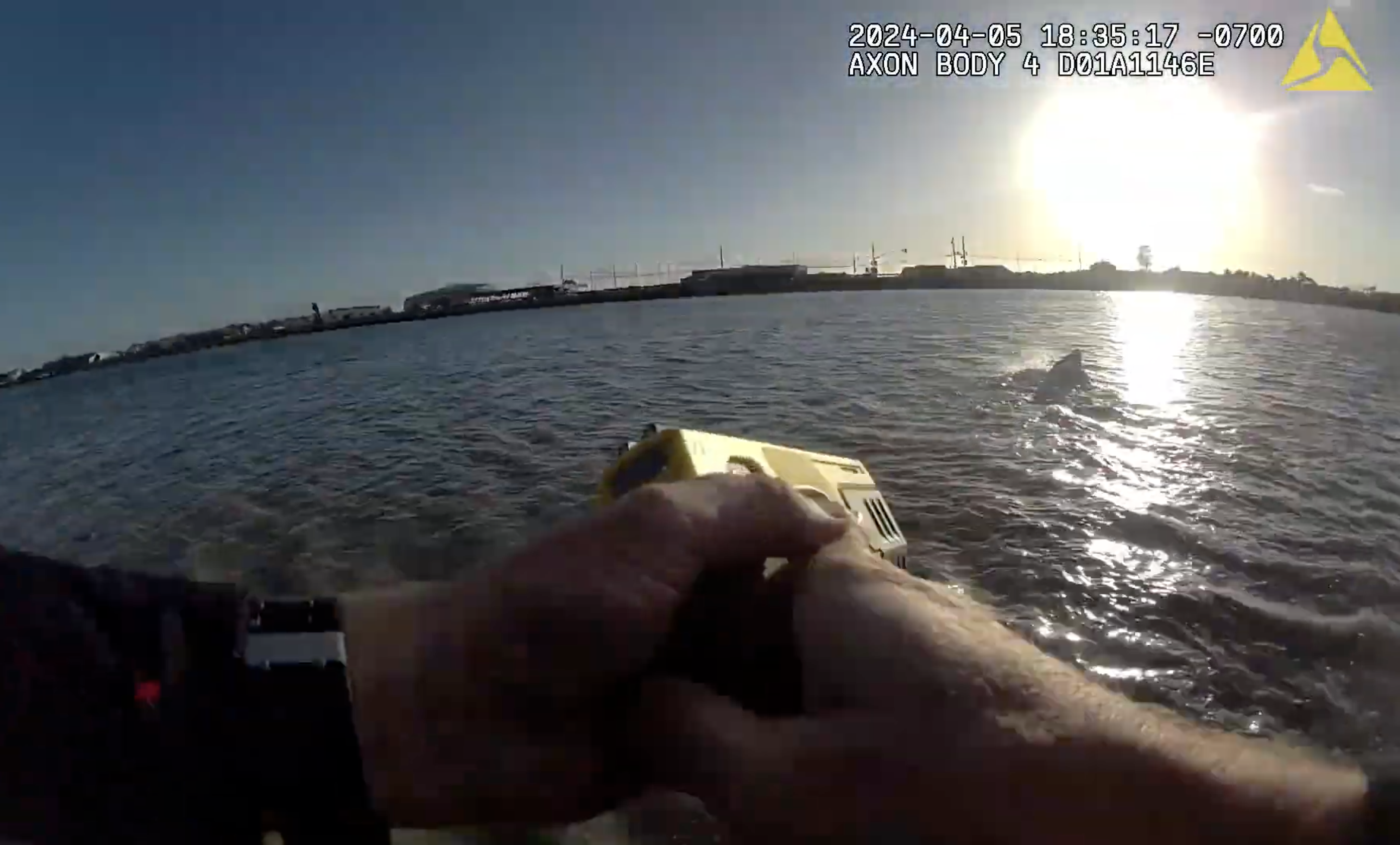 Someone pointing a Taser at a man in the water.
