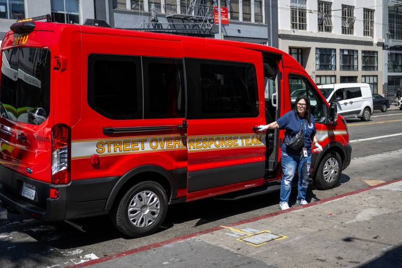 A middle-aged woman stands in front of a red van labeled 'Street Overdose Response Team'