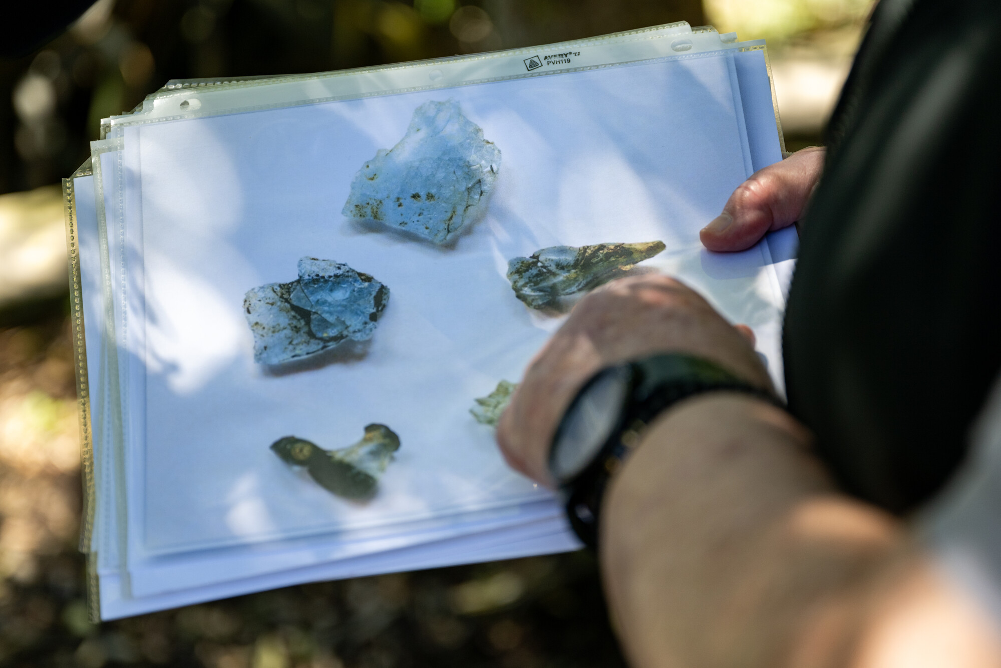 A person with a watch holds an image of blue-colored burned glass.