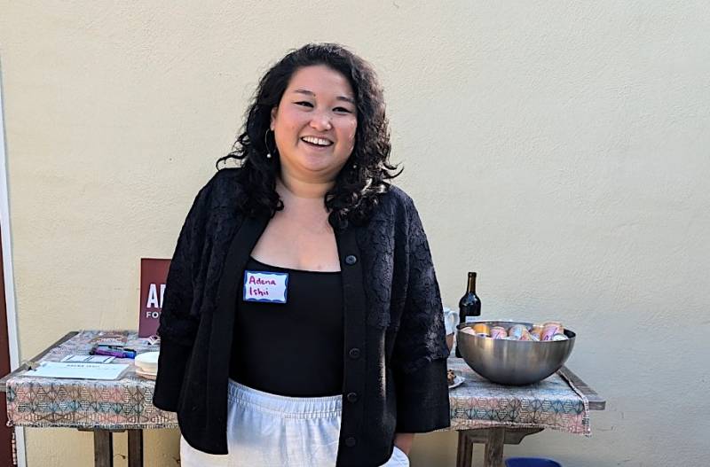 A young Asian woman stands in front of a table.