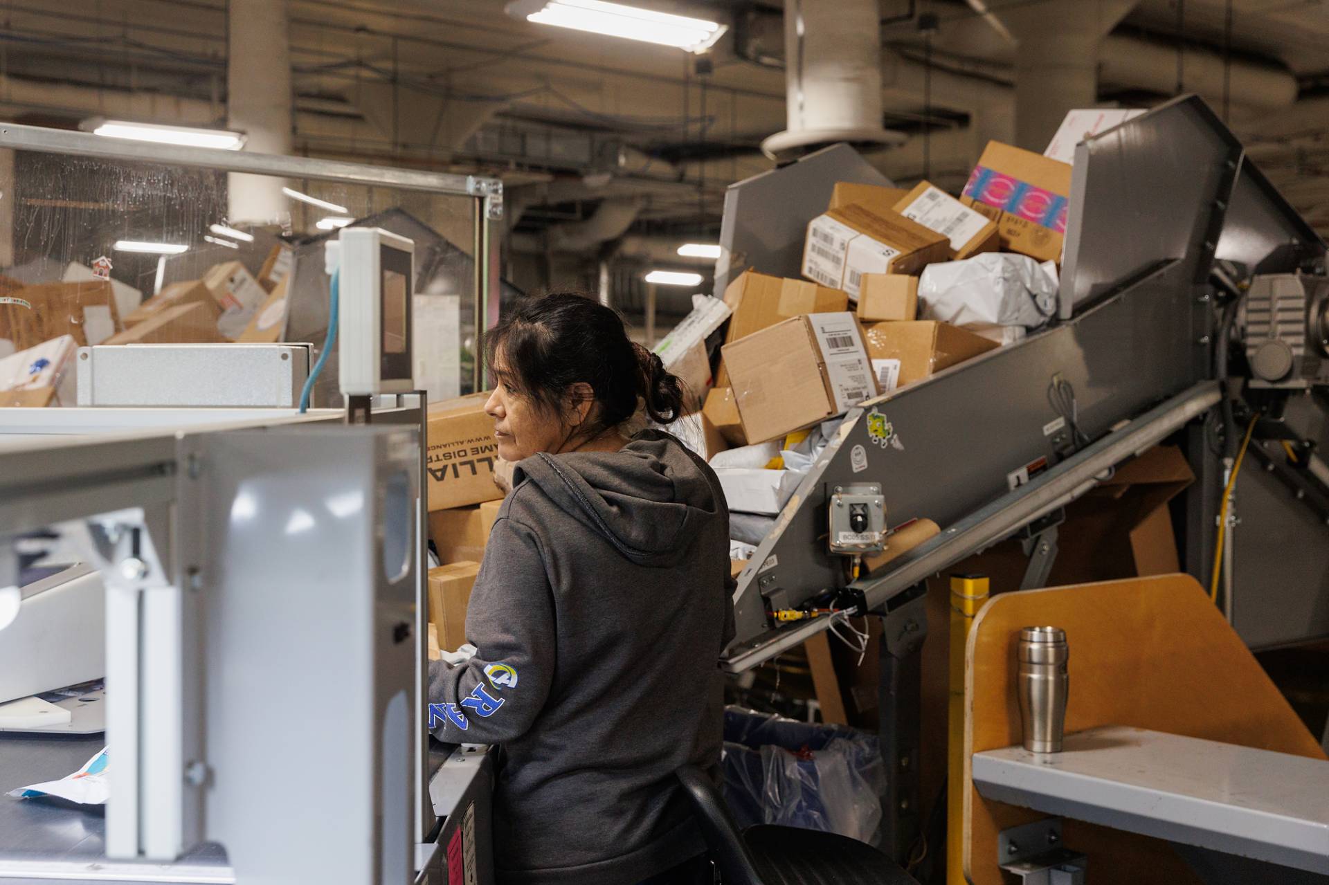 USPS clerk Maria Maldonado processes packages at her station during the holiday rush at the Processing and Distribution Center in Oakland, on Monday, Dec. 23, 2024. Juliana Yamada/KQED