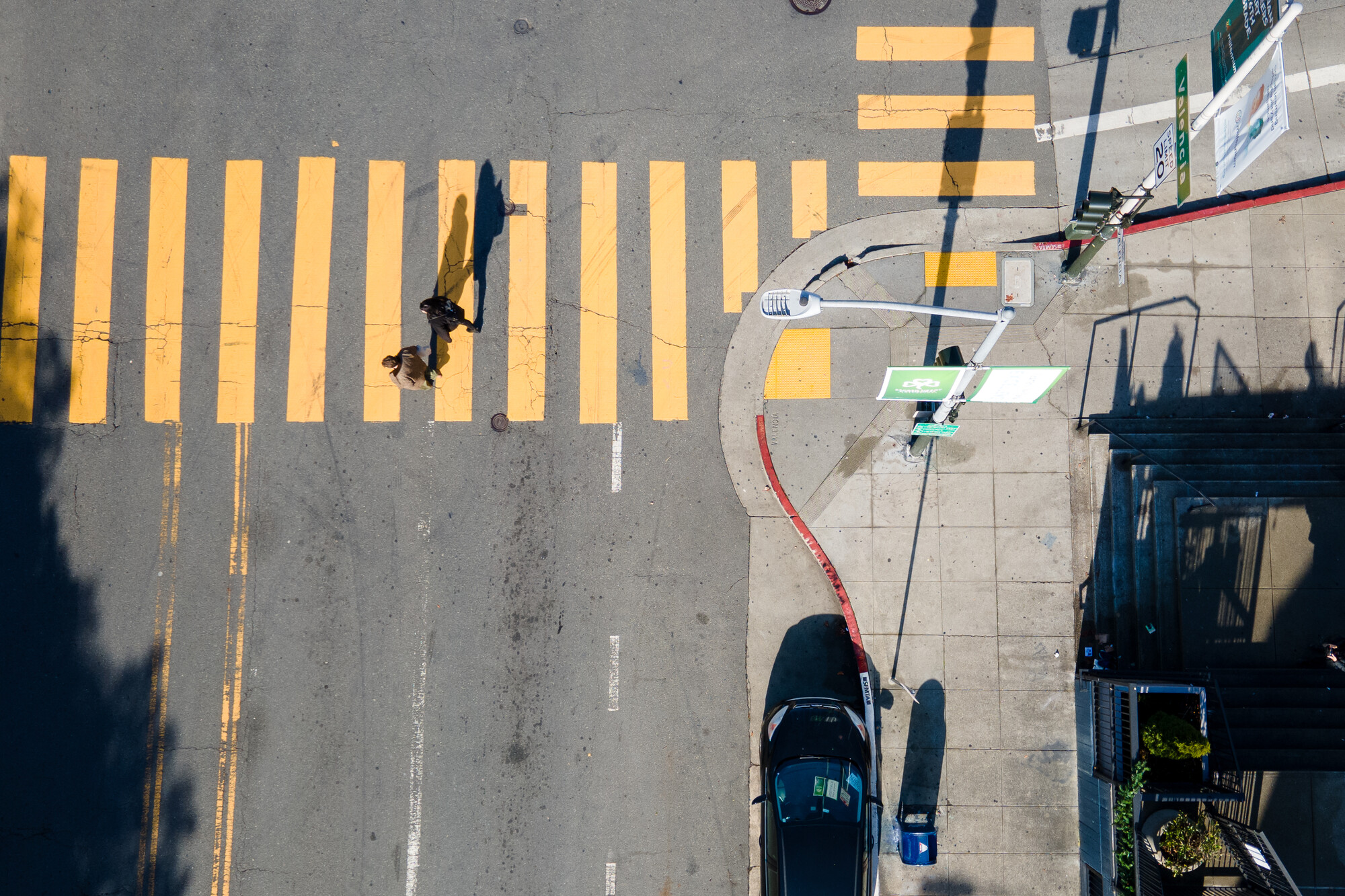 A person walks across a yellow-lined crosswalk.