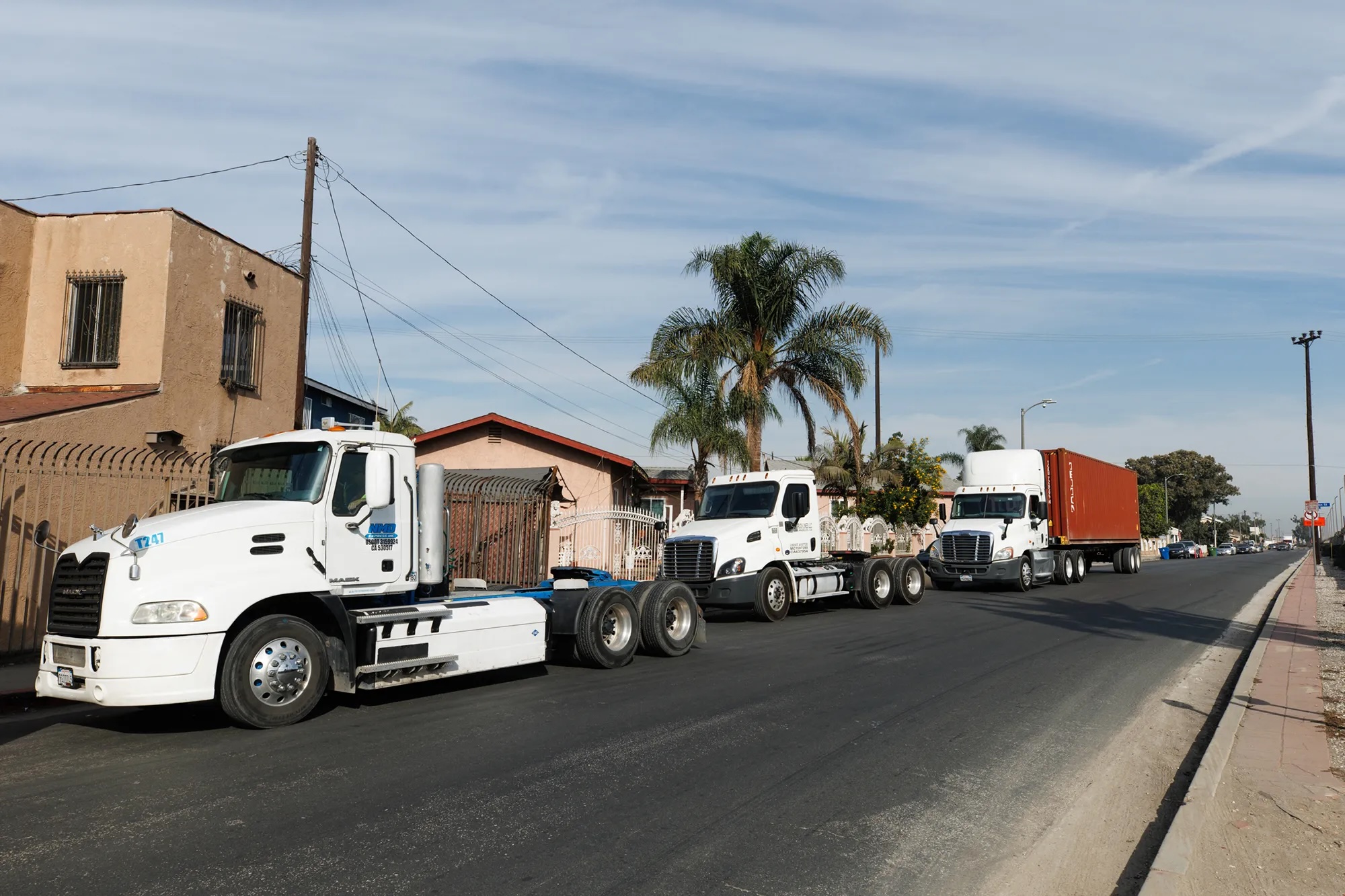 Diesel trucks parked by the side of a road in a residential area.