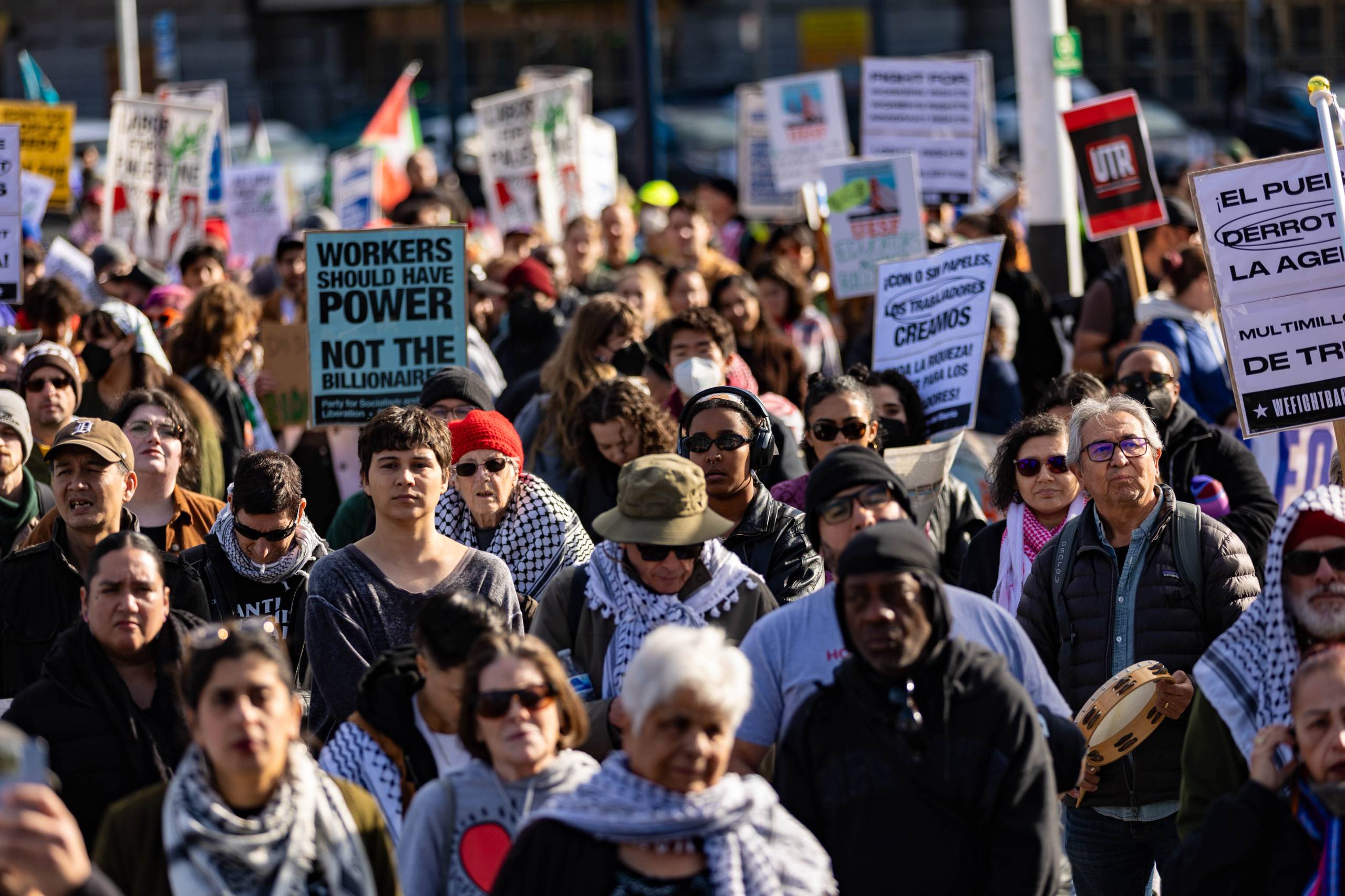 Several people in a large crowd hold signs and flags.