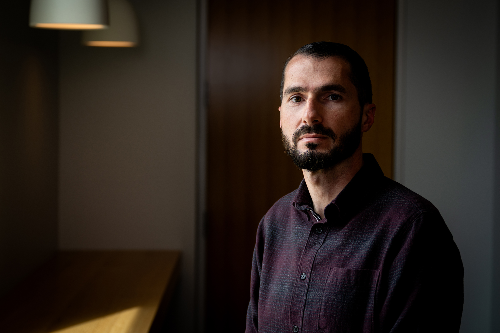 A young bearded man poses for a portrait.