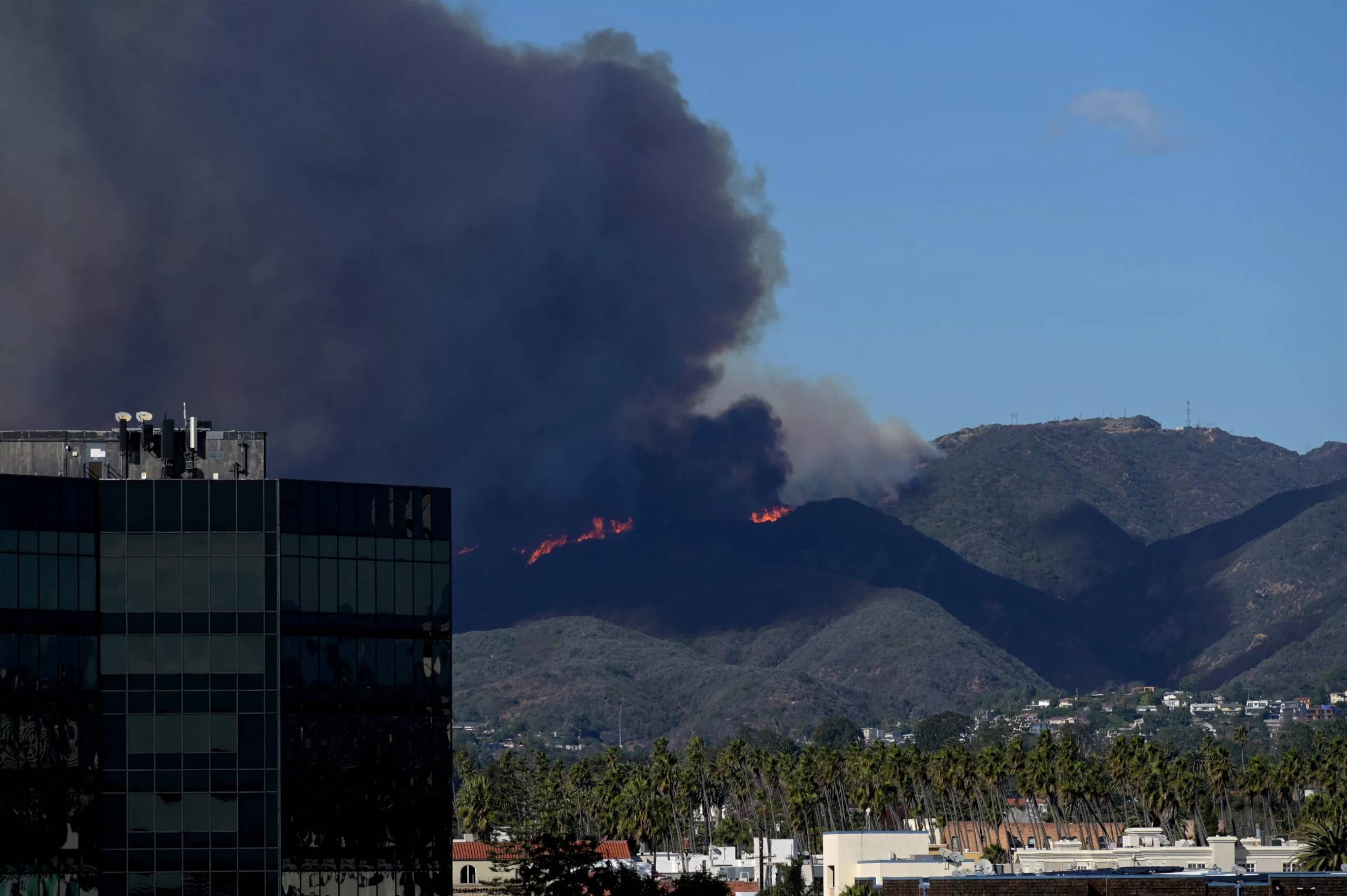 Flames and smoke on hilltops on the outskirts of Los Angeles, seen from downtown.