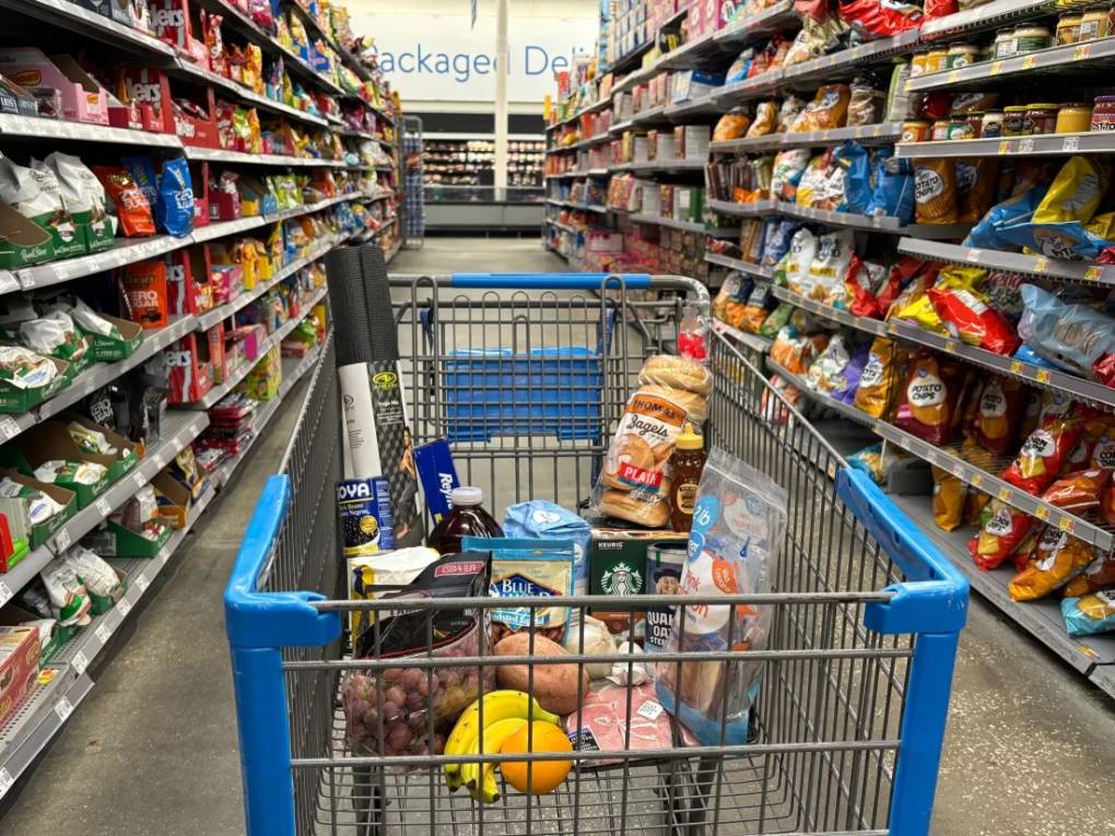 Items of shopping in a grocery store aisle, sitting in a shopping cart.