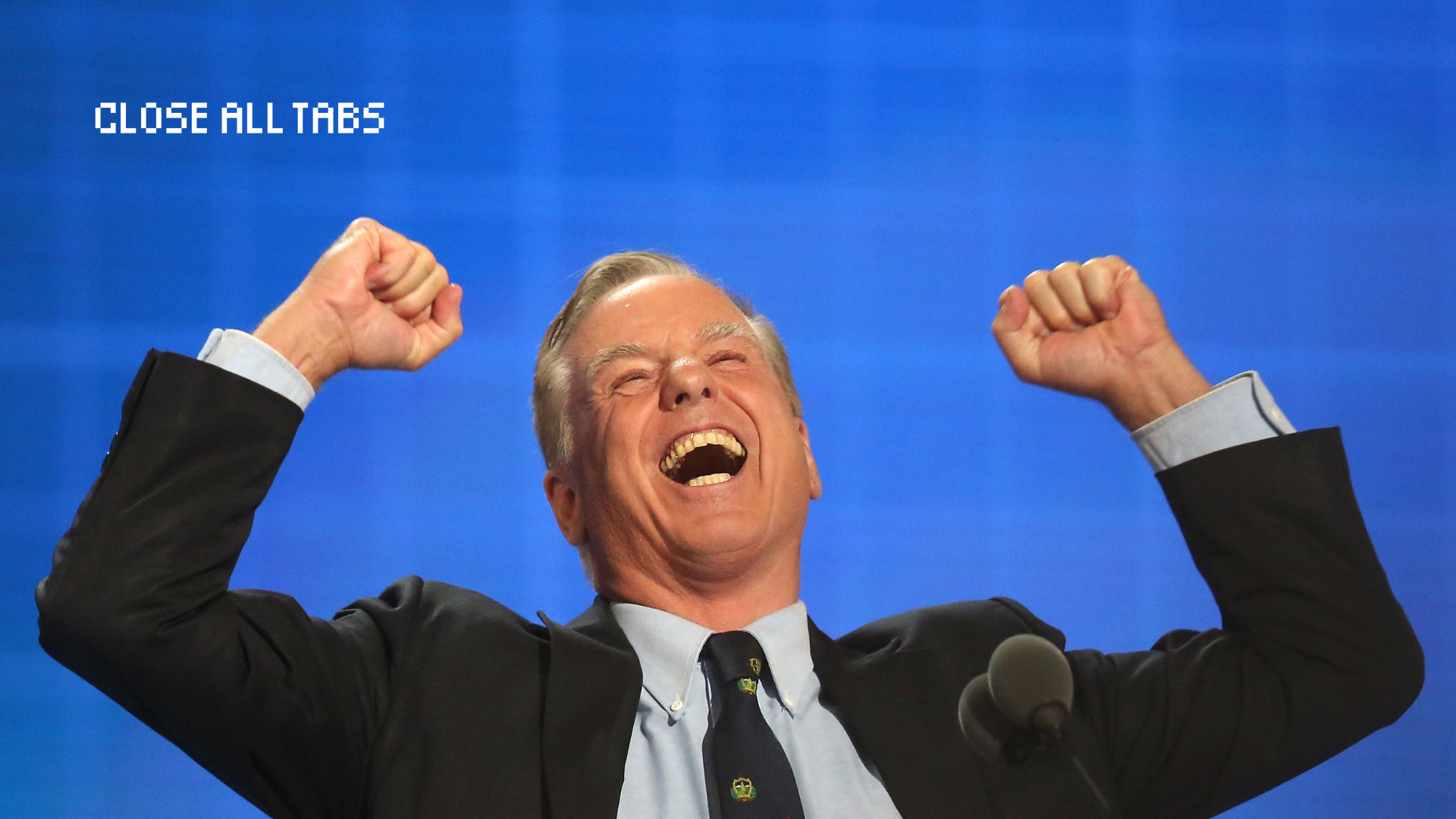 Howard Dean, a man with gray hair and wearing a suit, joyfully raises his fists in the air against a blue background.