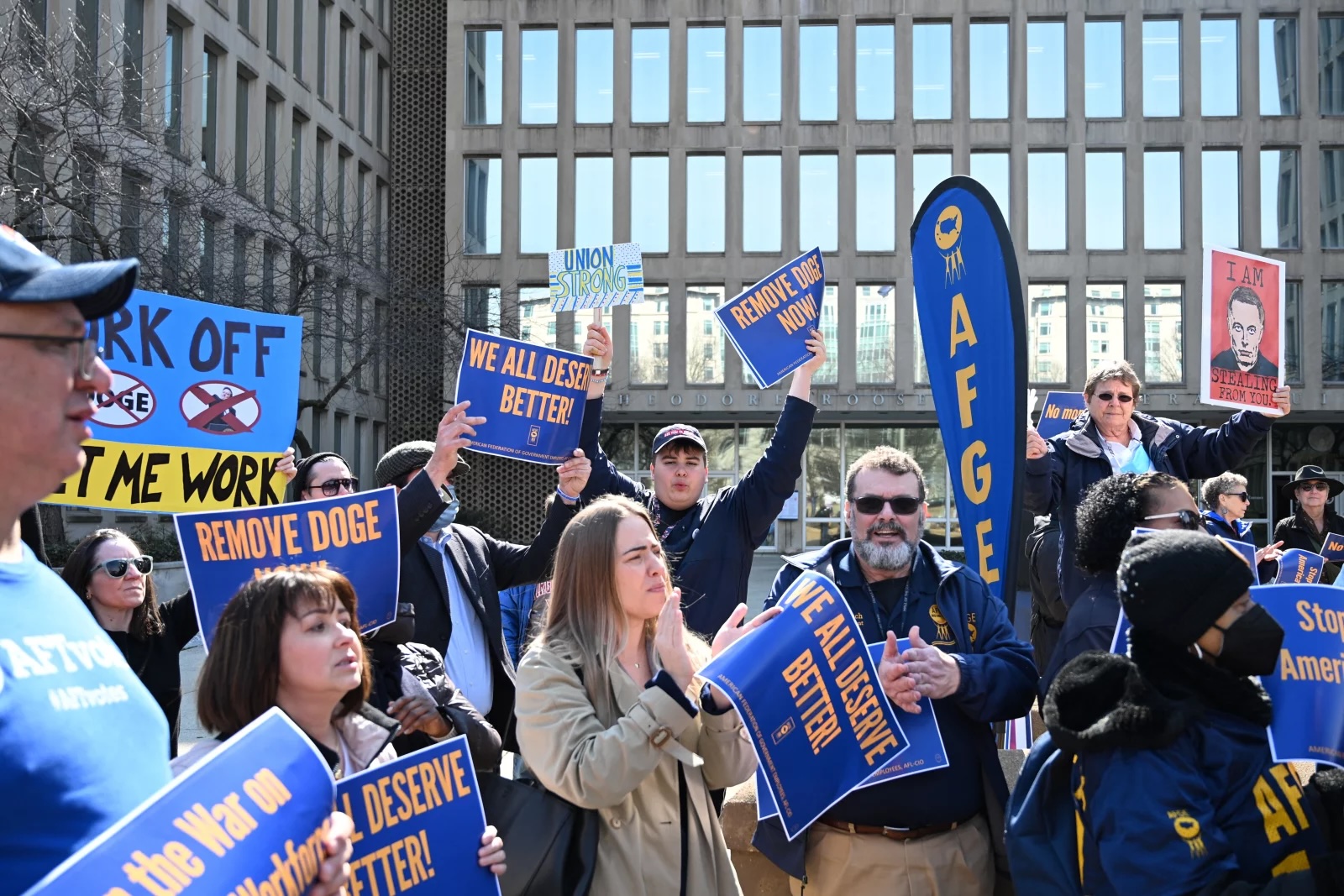 Protesters with banners and signs outside a building.