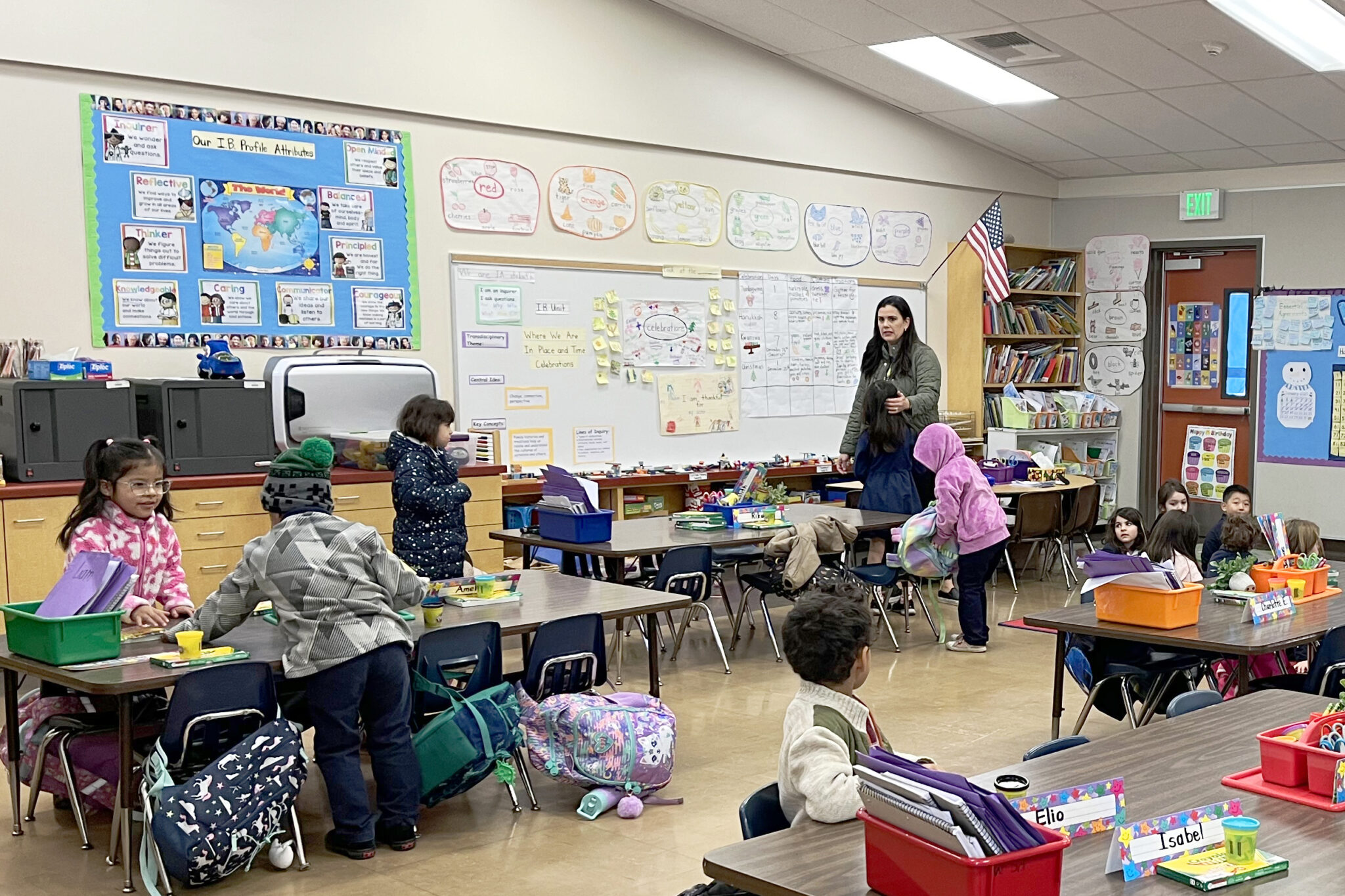 A woman stands in front of several children in a classroom.