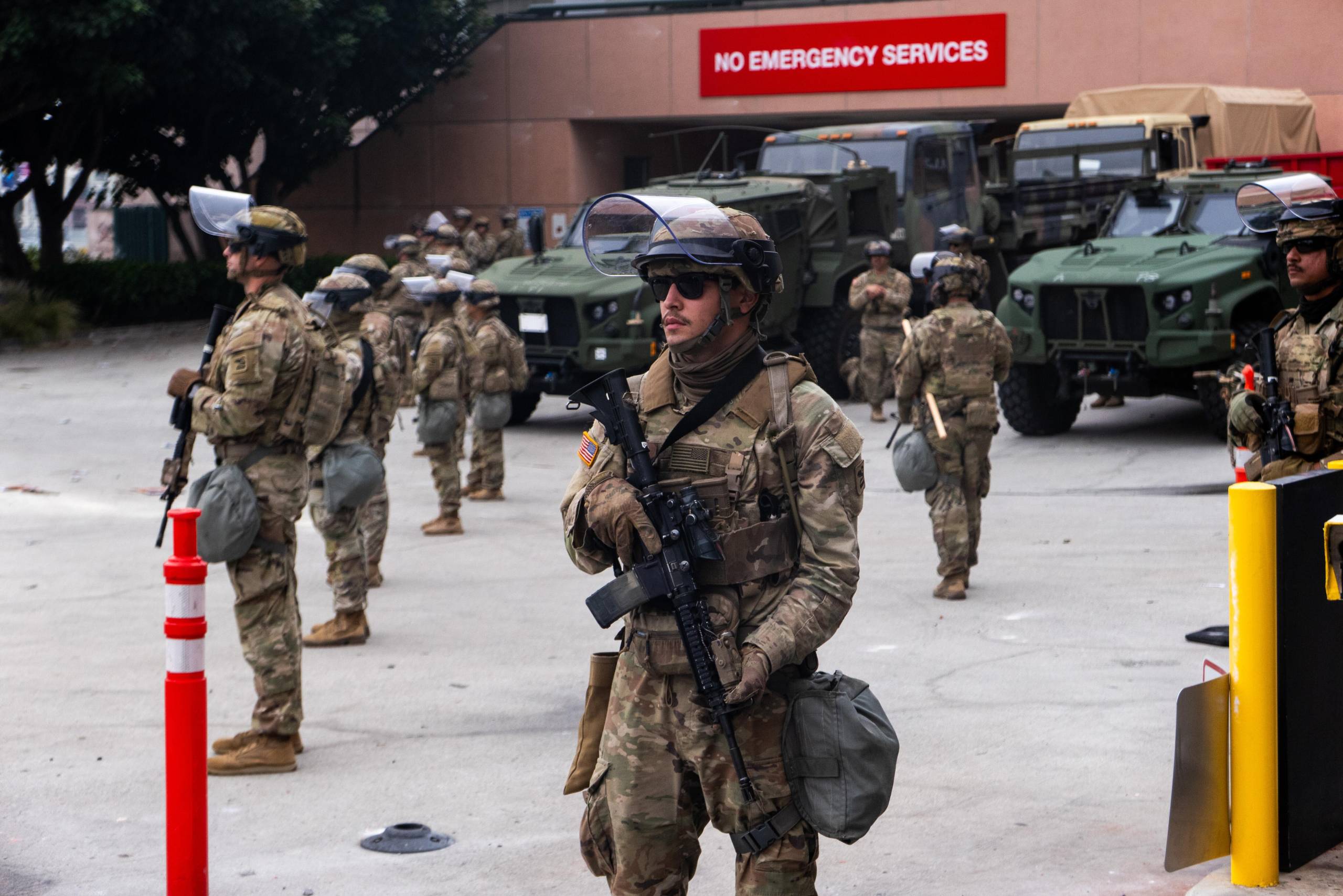 As tropas da Guarda Nacional ficam do lado de fora do Metropolitan Detenção Center no domingo, em Los Angeles. As tensões na cidade permanecem altas depois que o governo Trump chamou a Guarda Nacional contra os desejos dos líderes da cidade após dois dias de confrontos com a polícia durante uma série de ataques de imigração.