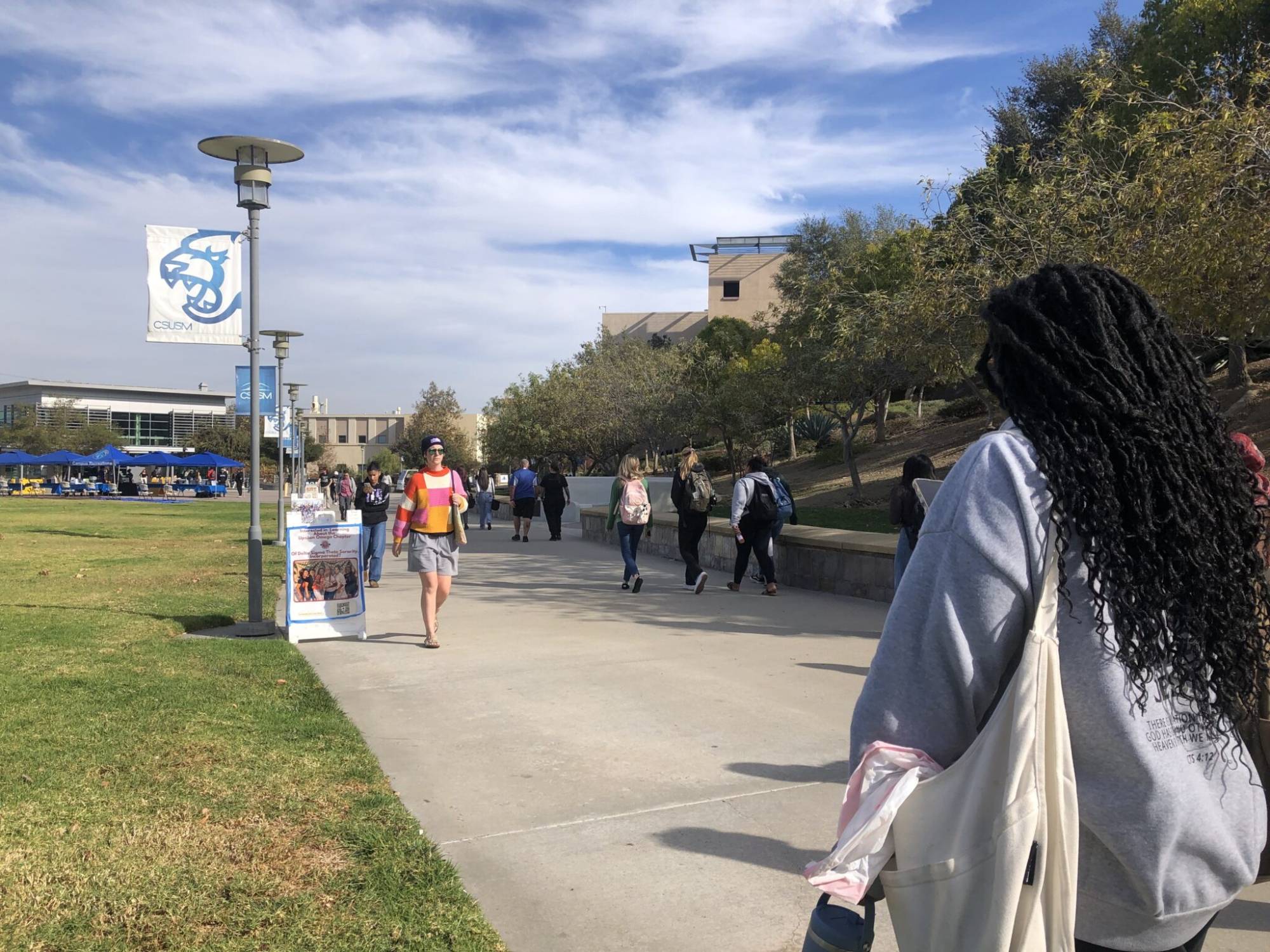 A view from a college campus of several people walking around.