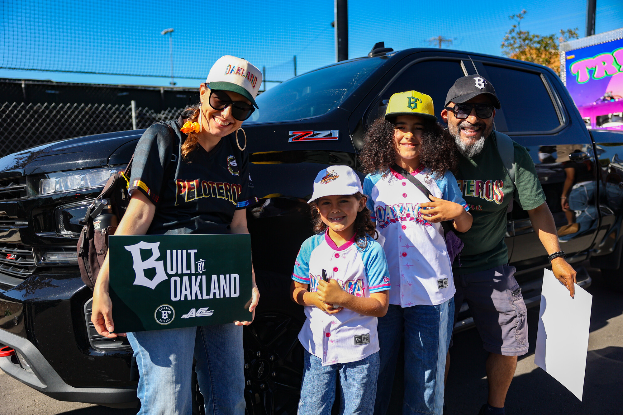 A man, woman and two young girls pose together in front of a car wearing similar clothing.