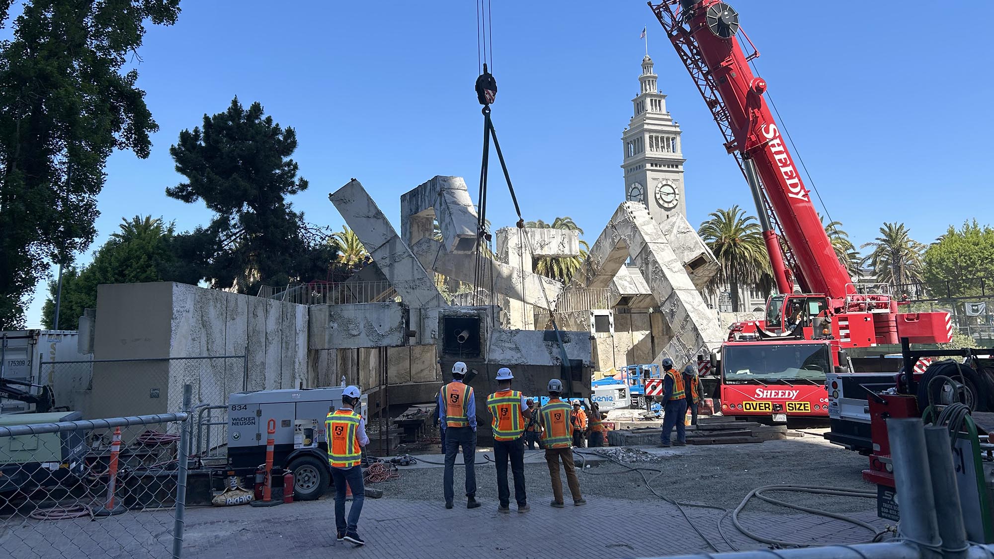 Construction crews watch as a large piece of the fountain is separated, and lowered down by a crane.