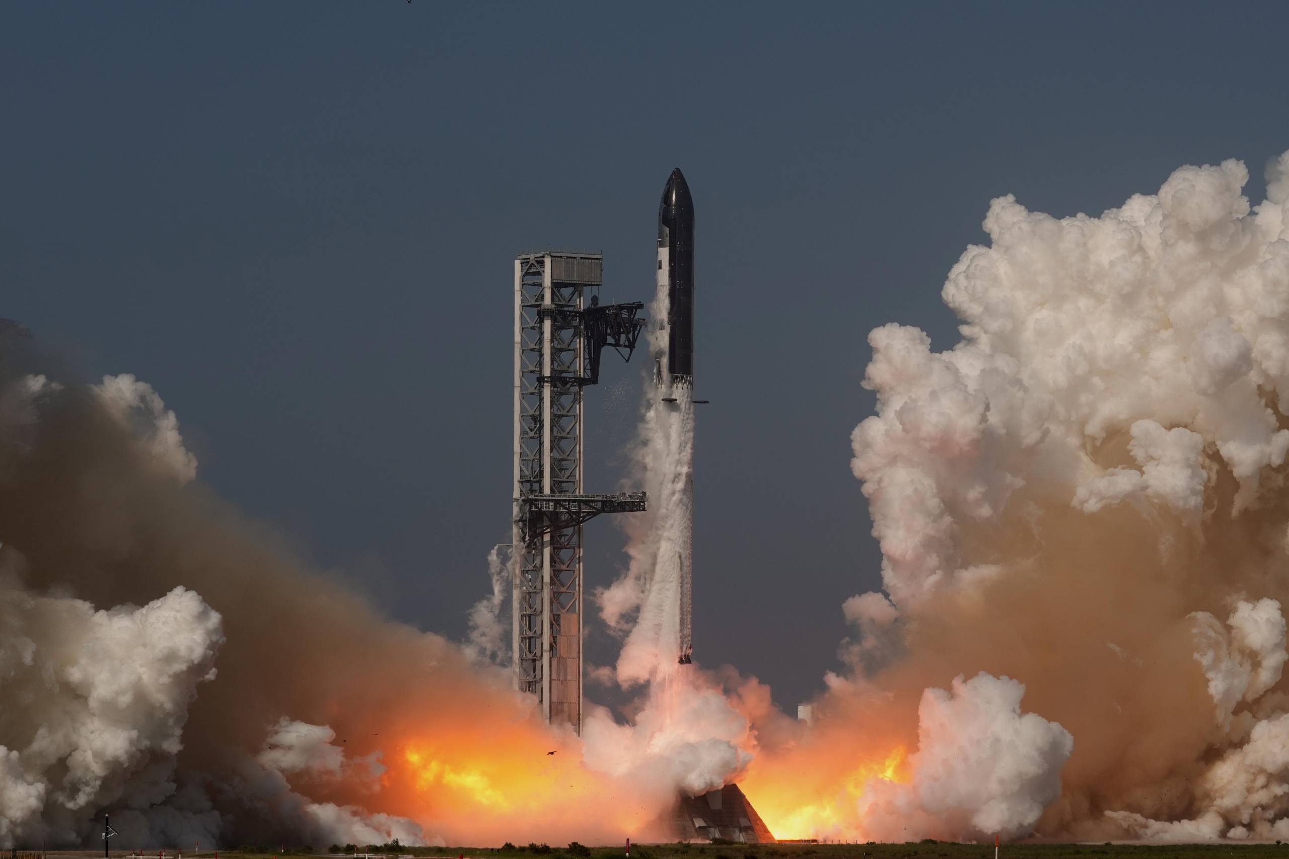 SpaceX's mega-rocket Starship blasts off from Starbase, Texas, on May 22. A plume of white gas extends from the bottom of the rocket, which is vertically taking off from the ground. Large clouds of white gas are on the right and left sides of the frame.