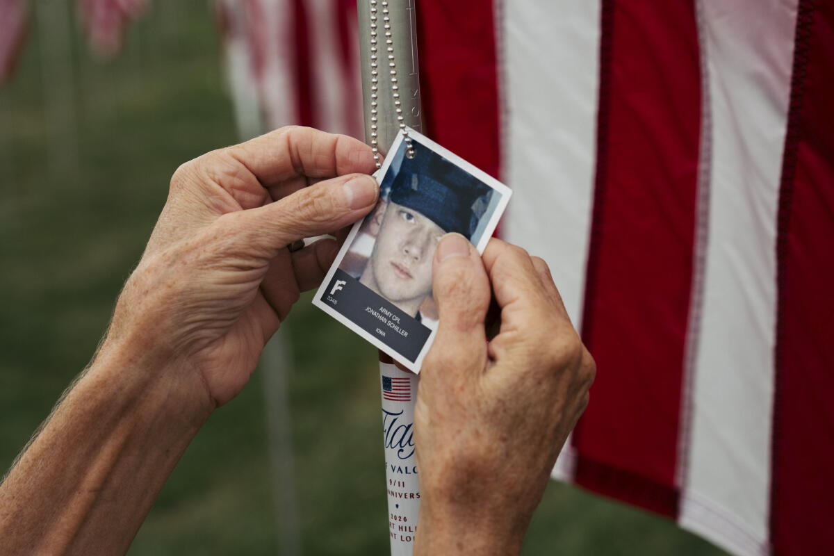 Suzi Mahe, a 66-year-old volunteer from University City, Mo., adjusts a portrait honoring Army Cpl. Jonathan Schiller of Iowa at the 'Flags of Valor' installation on Thursday, Sept. 10, 2026, at Art Hill in Forest Park, St. Louis. More than 7,600 American flags honor service members, first responders and civilians who died in the Sept. 11th attacks and subsequent military conflicts.