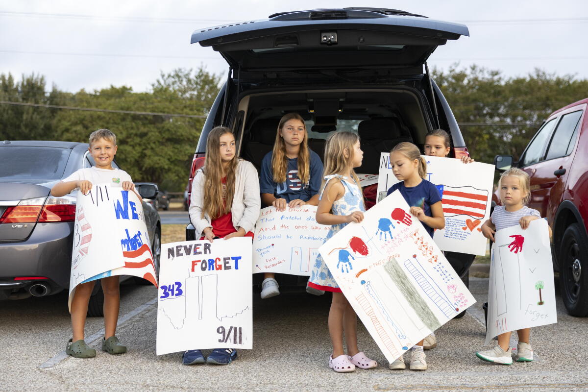 Brooks Penny, 9, Harper Penny, 12, Mabrey Penny, 11, Isla Penny, 6, Charlotte Zwolinski, 6, Kensie Zwolinski, 9, and Madelyn Zwolinski, 4, holds their posters up for the Austin fire fighters during the annual Austin Fire Department Memorial Stair Climb at Pleasant Valley Tower on Friday. Austin firefighters climbed the tower until they reached 1,386 feet, the height of the World Trade Center, to pay tribute to firefighters who died on 9/11.