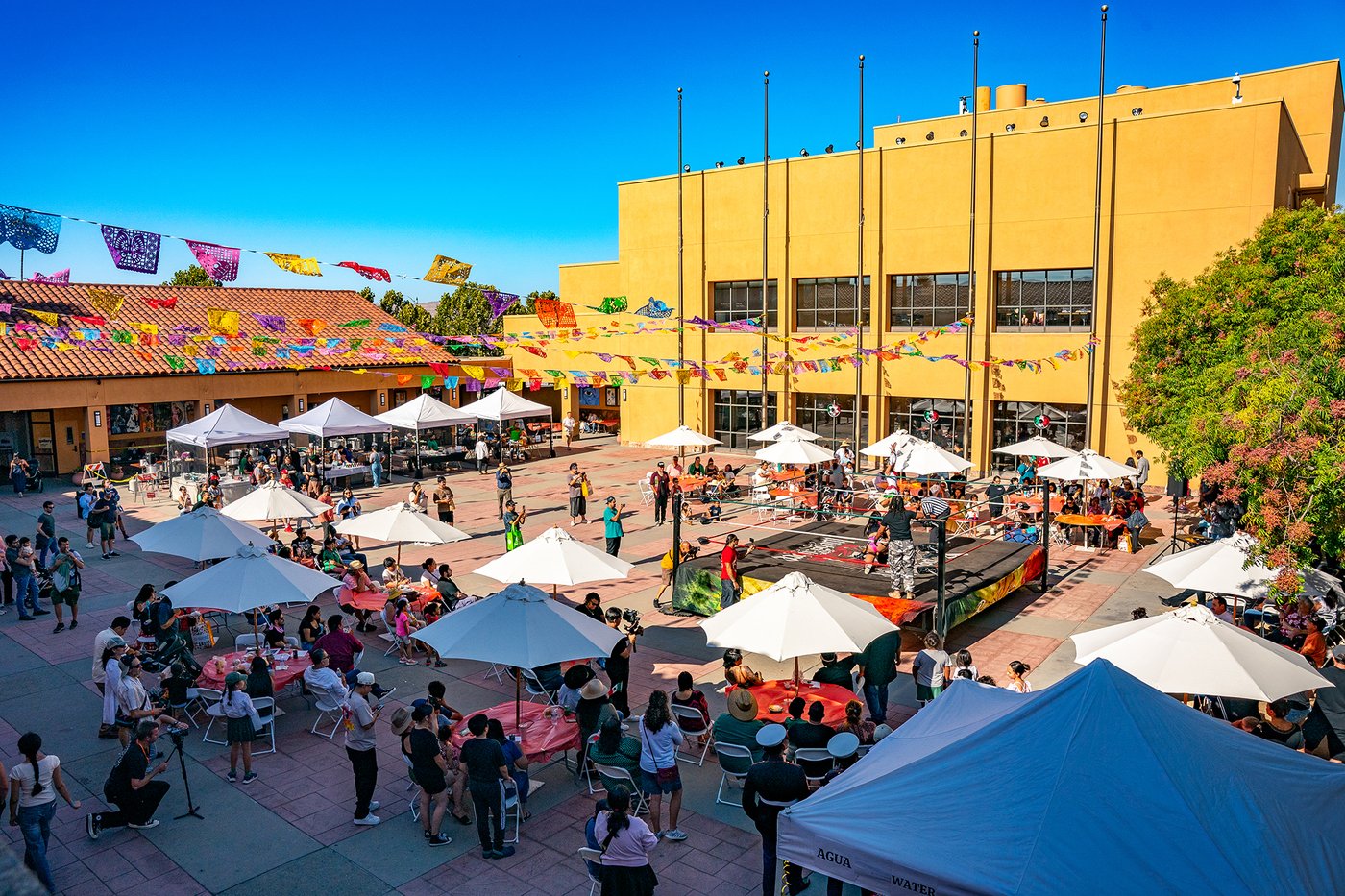Tents, umbrellas and crowds fill the plaza at the Mexican Heritage Plaza in San José under strings of papel picado.