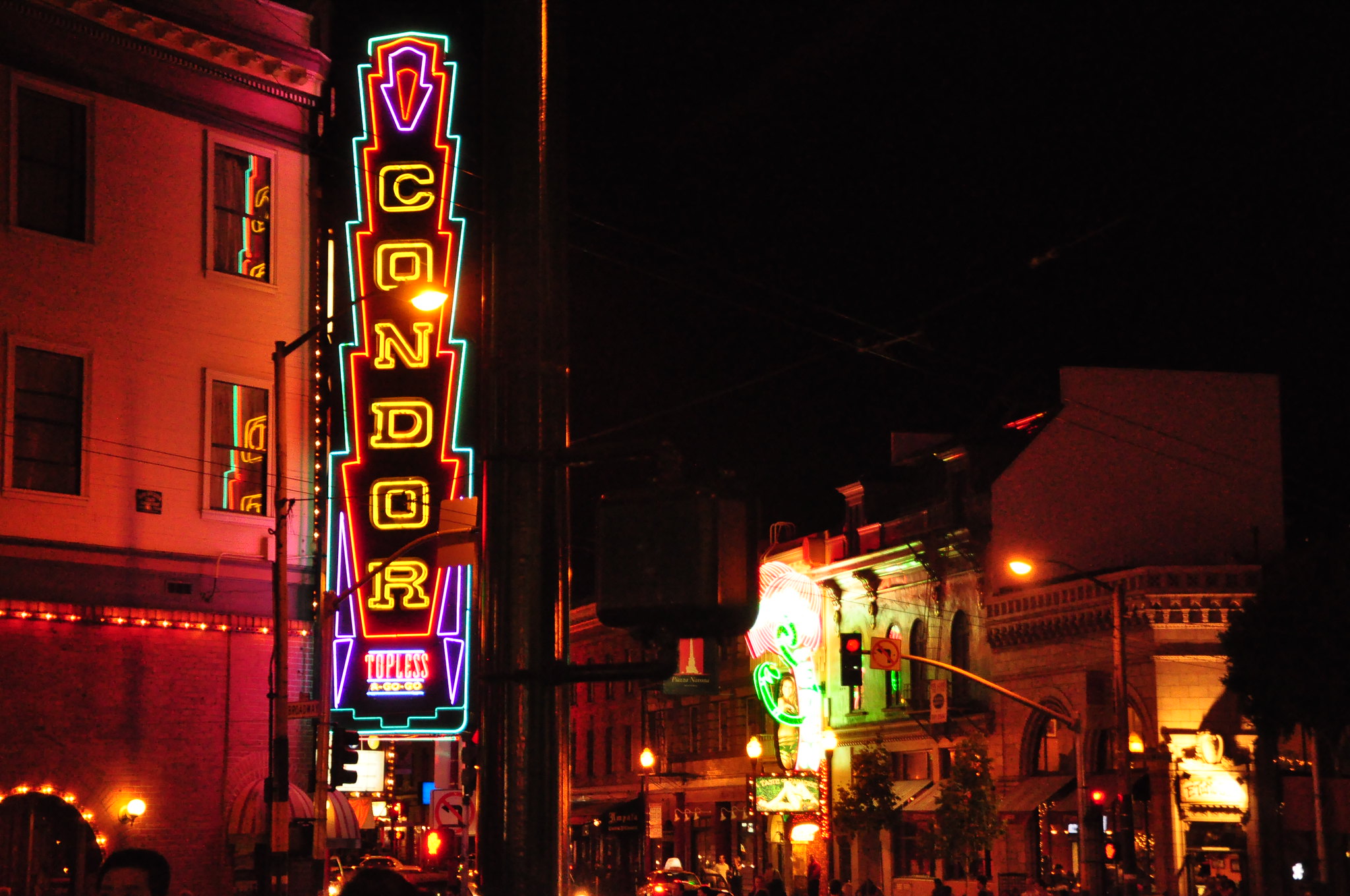 A large neon sign glows brightly on a darkened street, reading Condor.