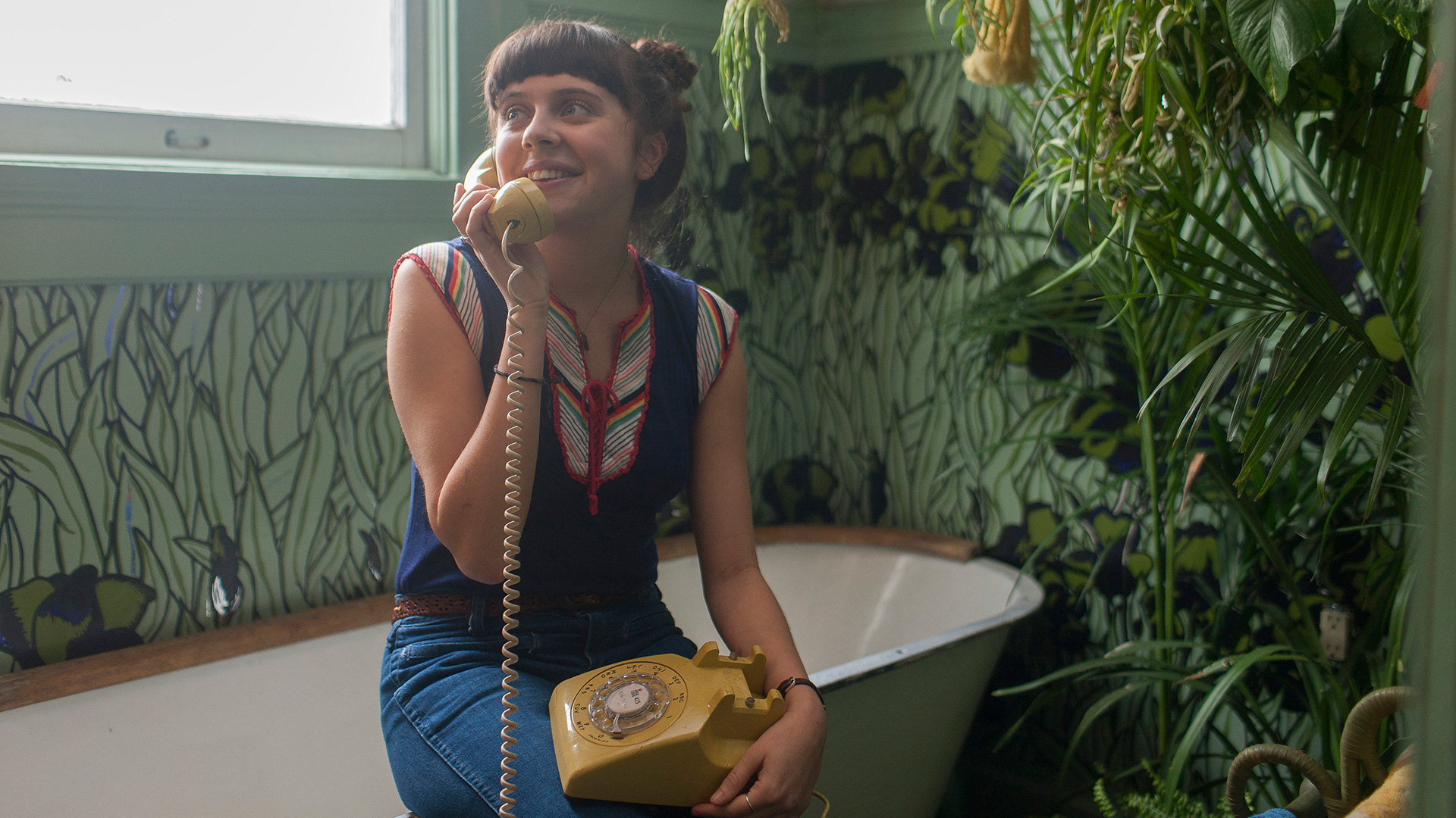 girl sits on tub edge smiling while on phone