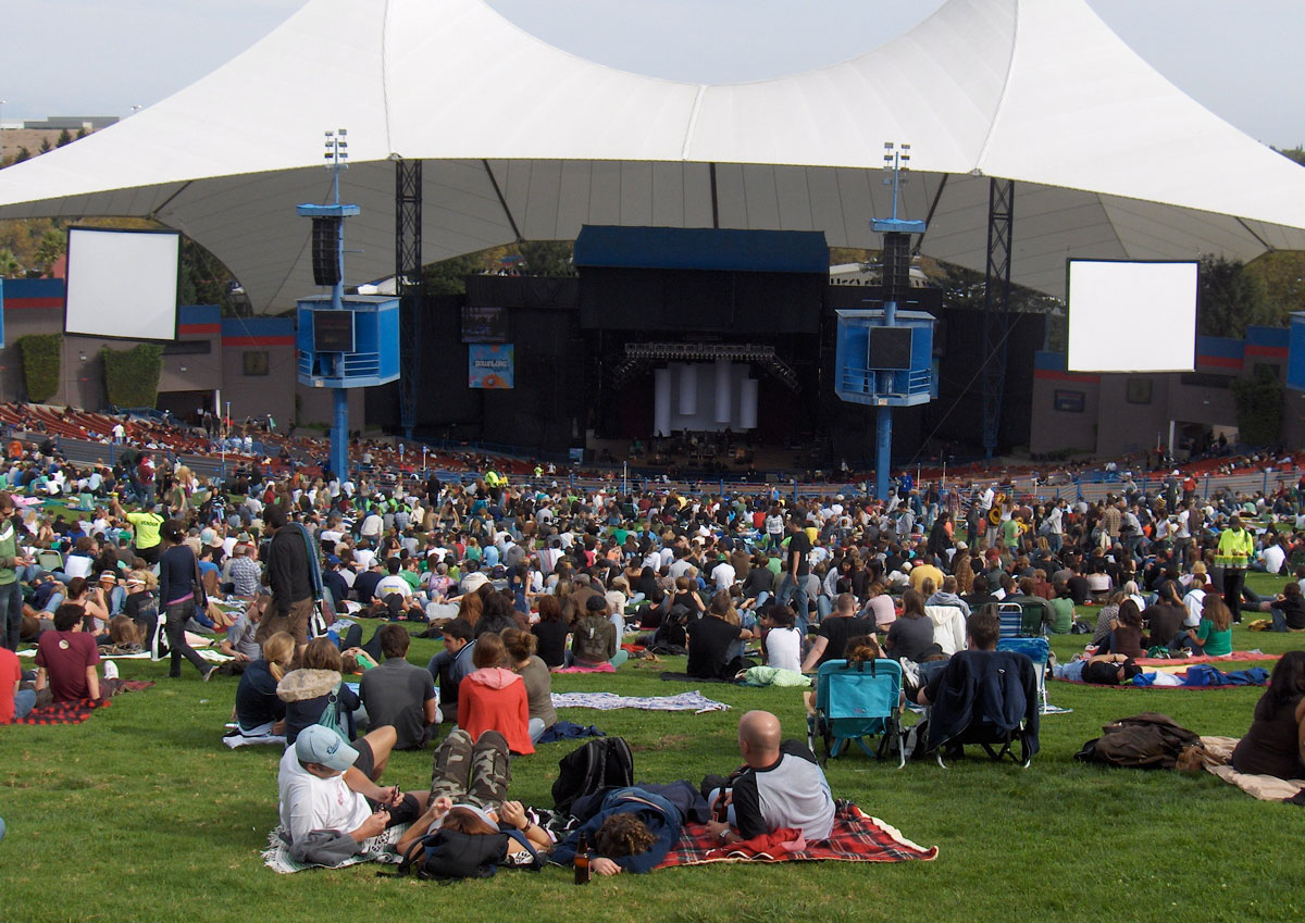 A large concert venue with people sitting on the lawn.